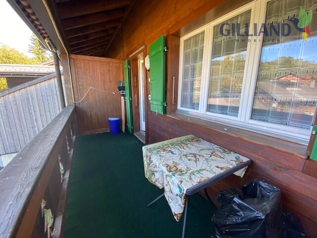 Überdachte Holzterrasse mit Tisch und Fensterfront