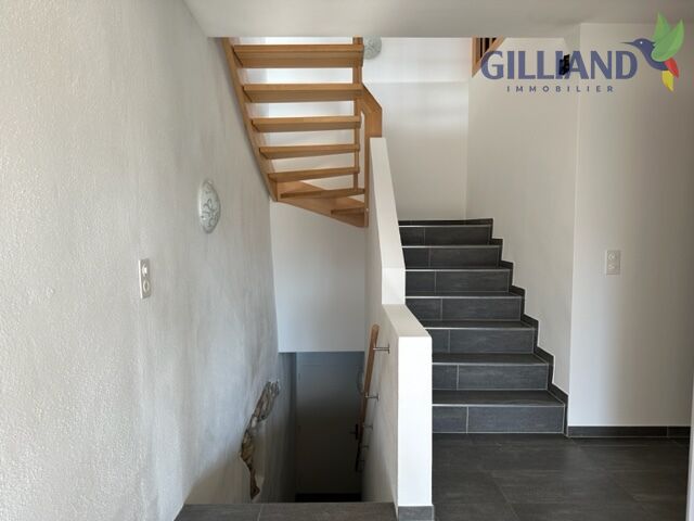 Treppenhaus mit Holztreppe und dunklem Fliesenboden