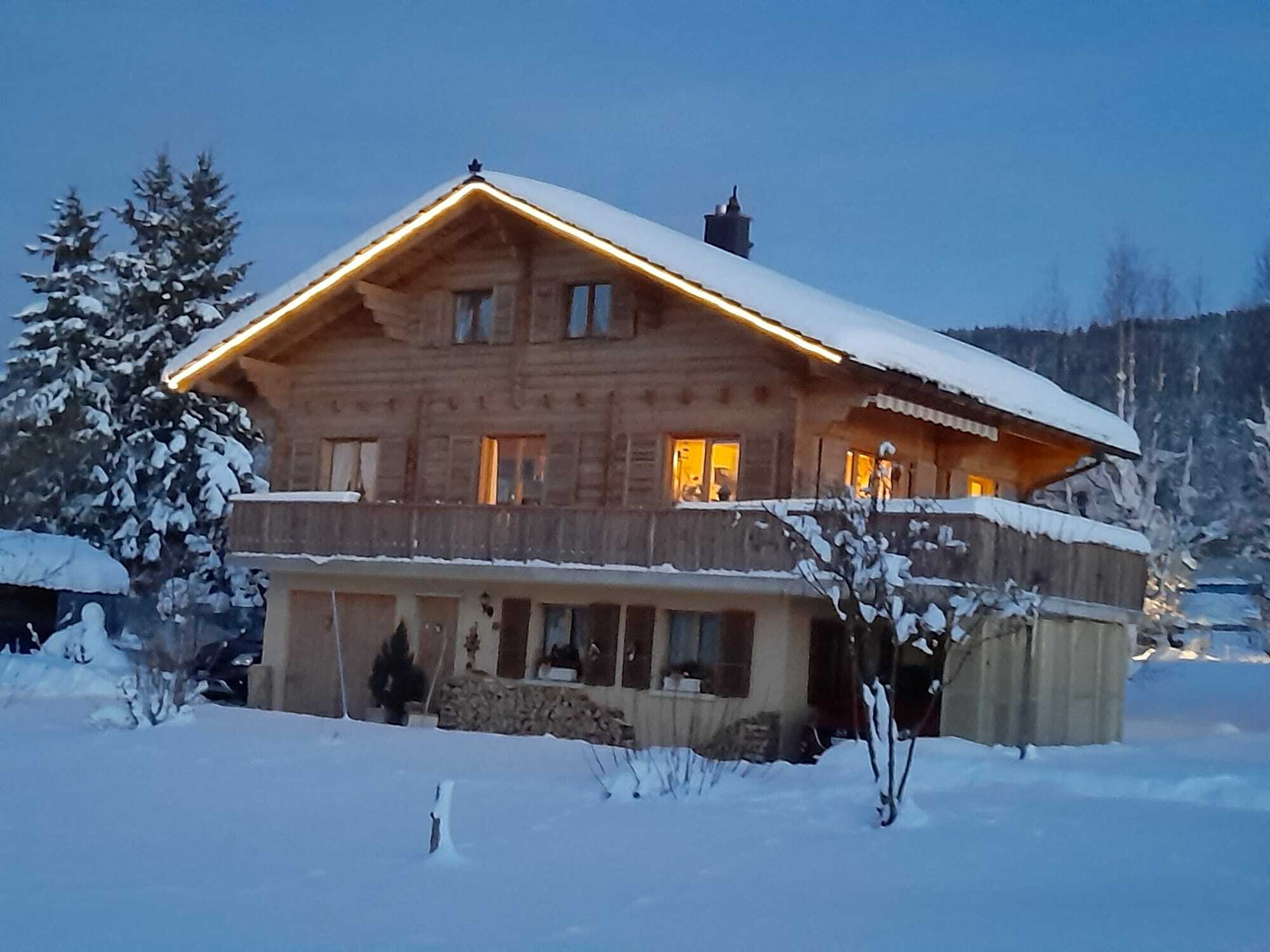 Alpines Holzhaus im Schnee bei Dämmerung