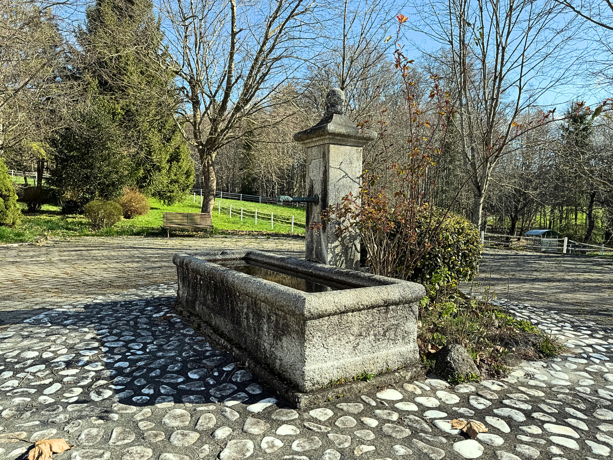 Steinbrunnen in einer parkähnlichen Außenanlage