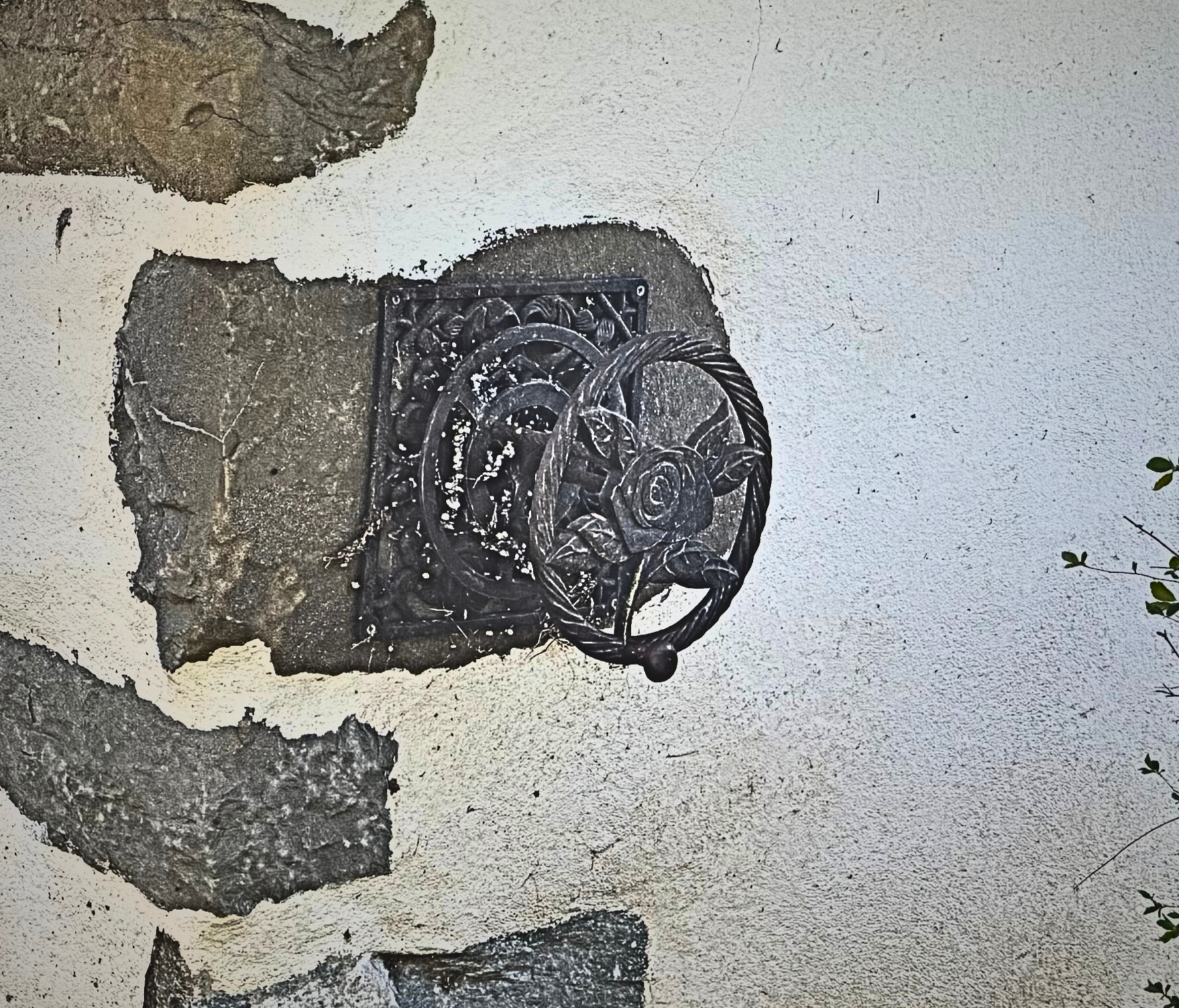 Außenwand mit beschädigtem Putz und dekorativem Metallelement