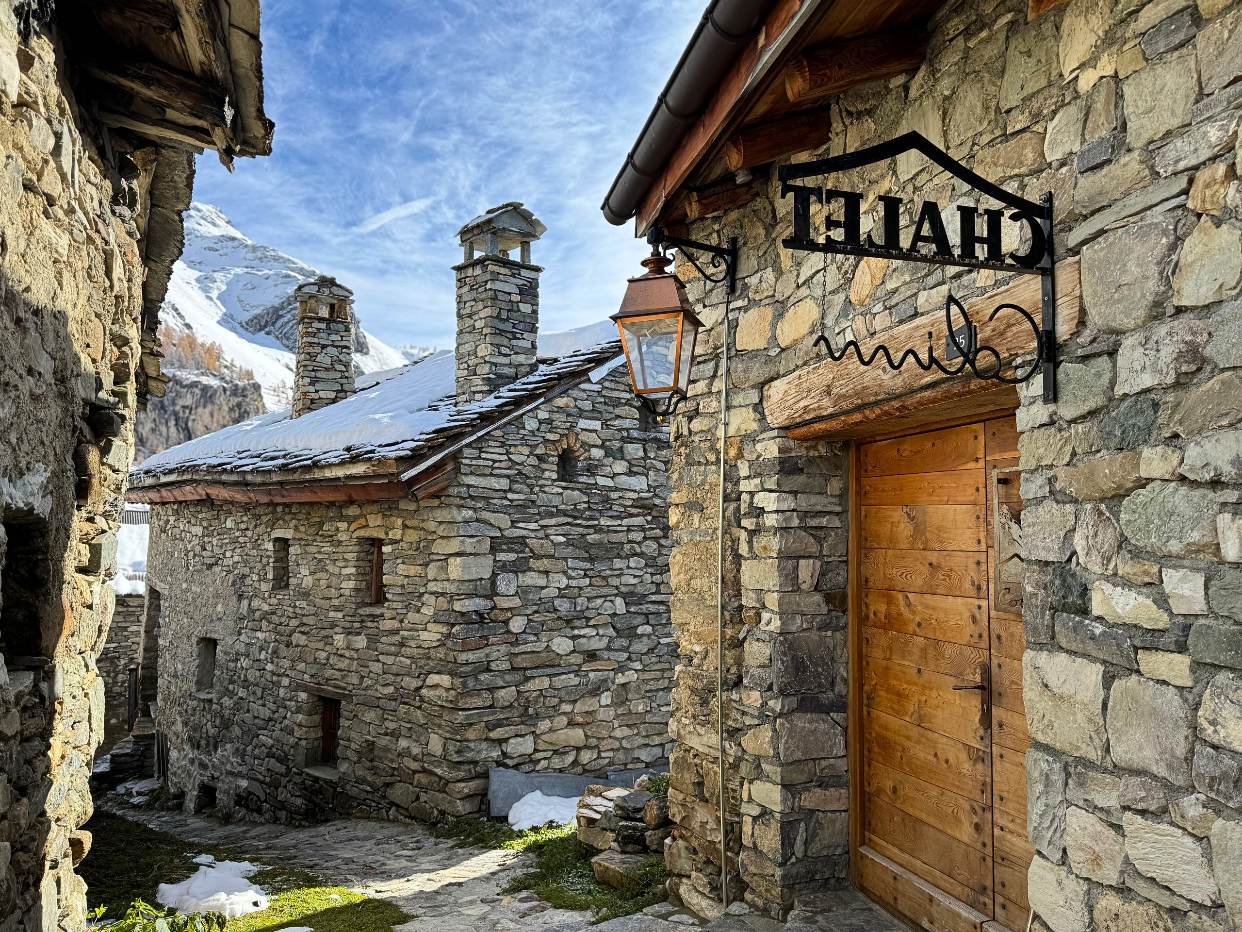 Alpine Dorfgasse mit Steinfassaden und Schneeblick