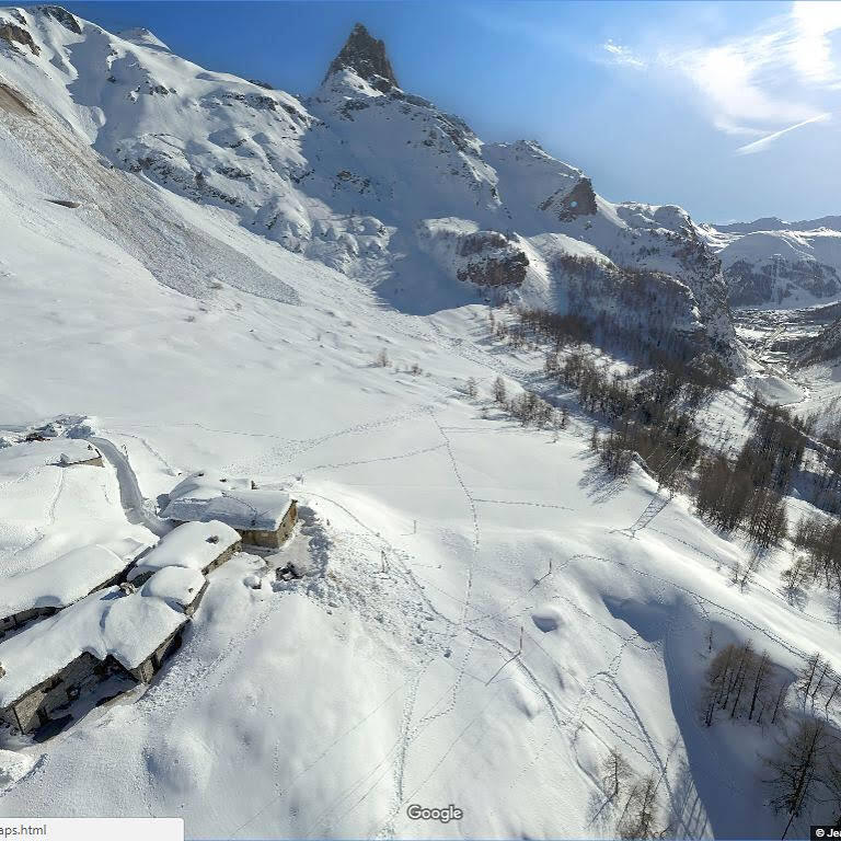 Schneebedeckte Berglandschaft mit Tal und einzelnen Gebäuden