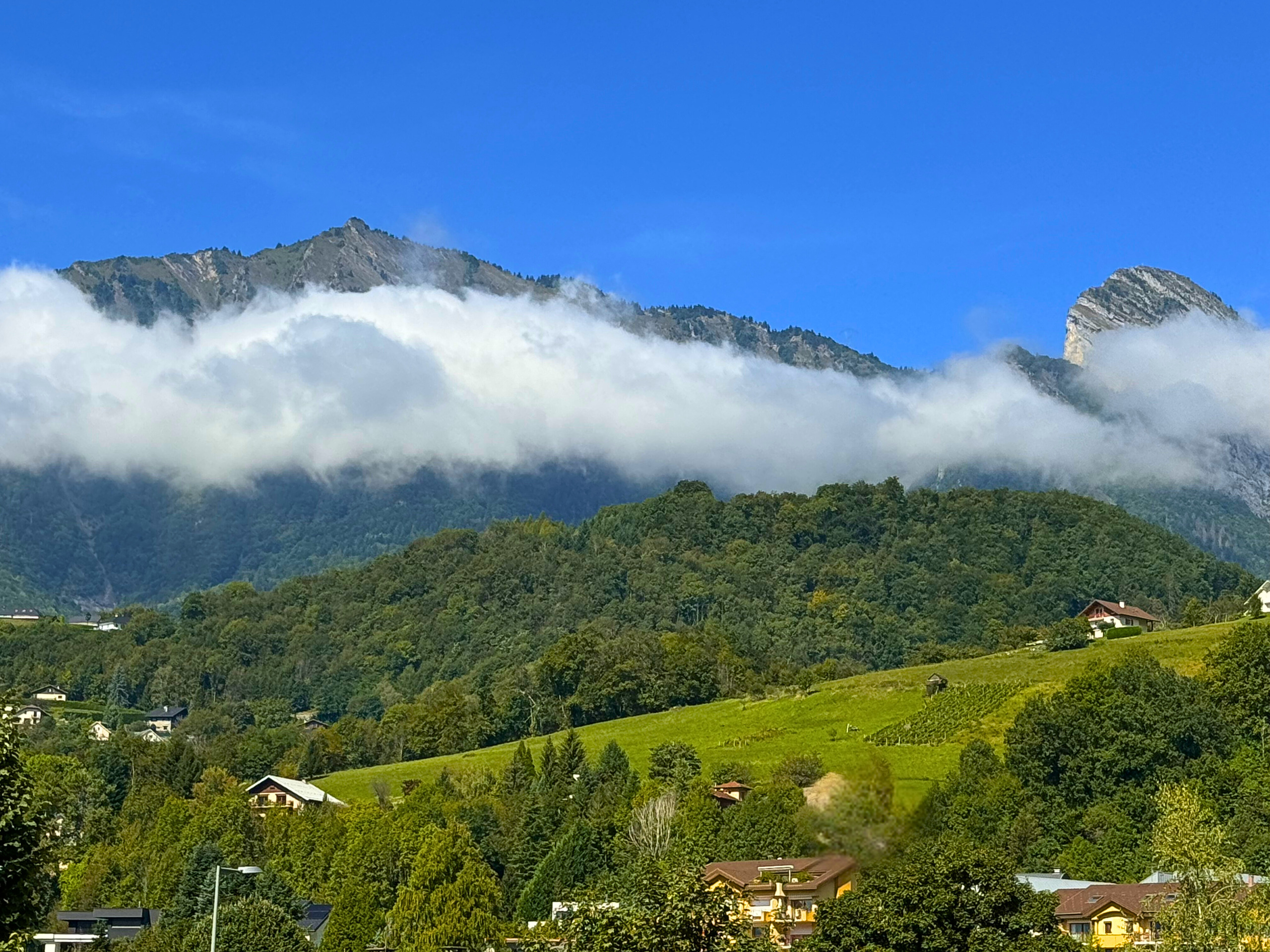 Berglandschaft mit Wolken und Talbebauung