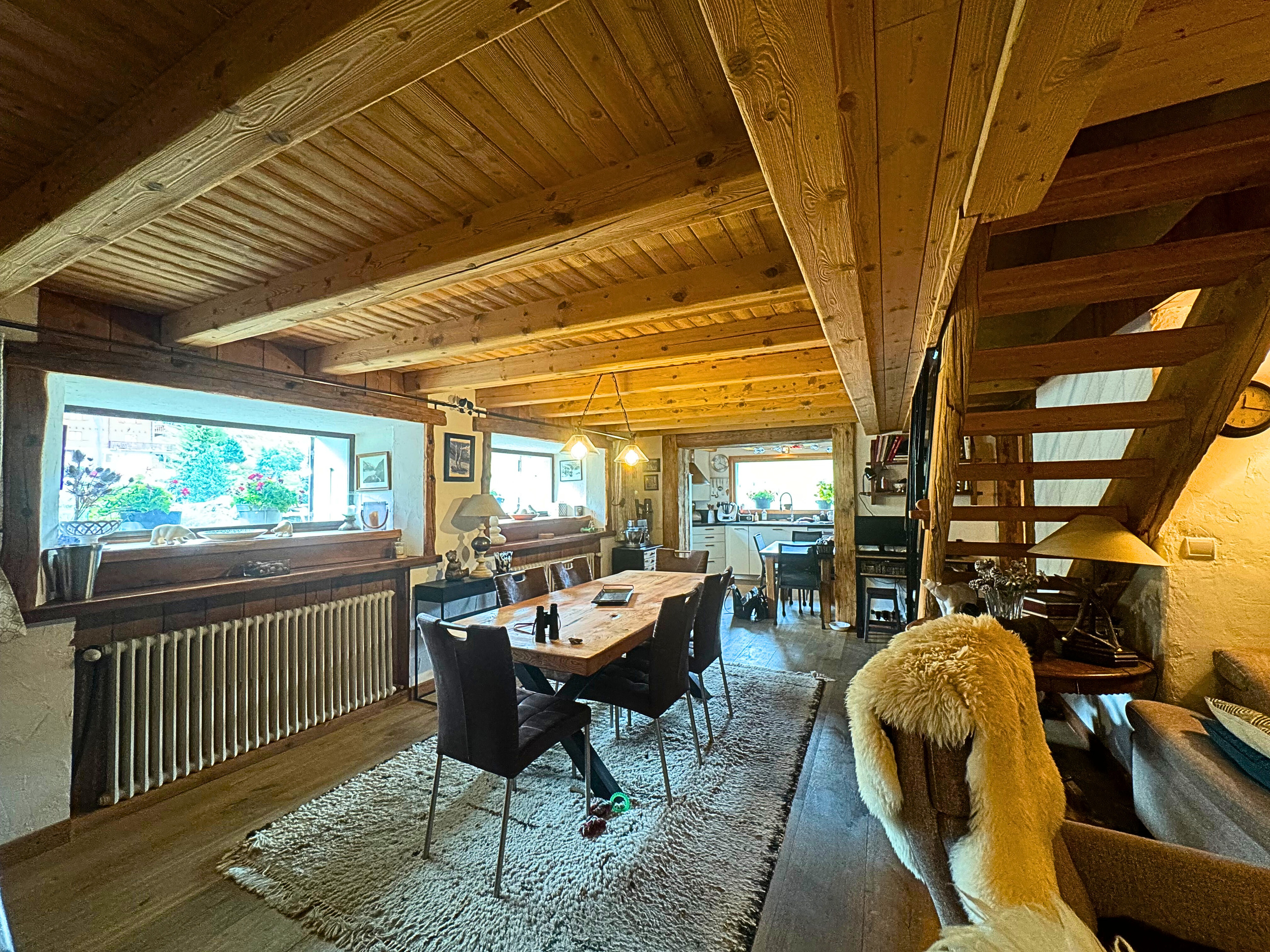 Gemütlicher Wohn- und Essbereich mit sichtbarer Holzbalkendecke