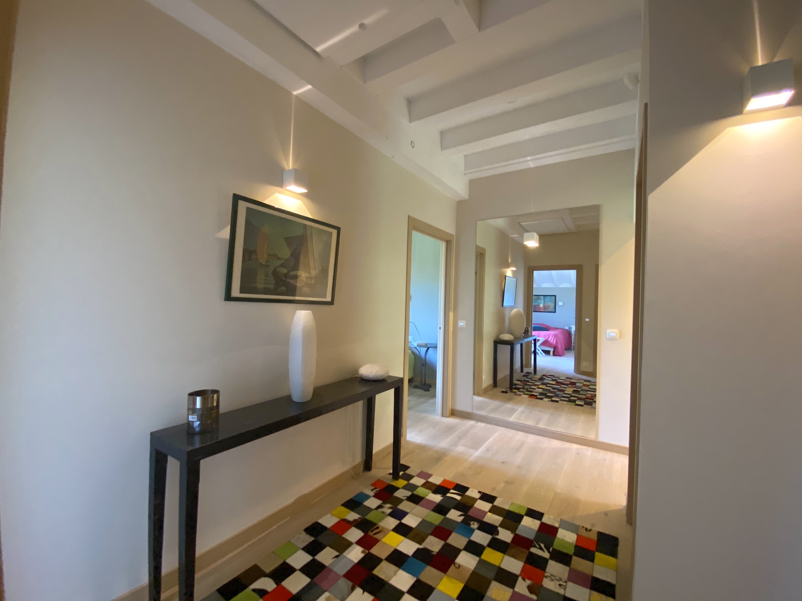Heller Flur mit Kunst und farbigem Teppich