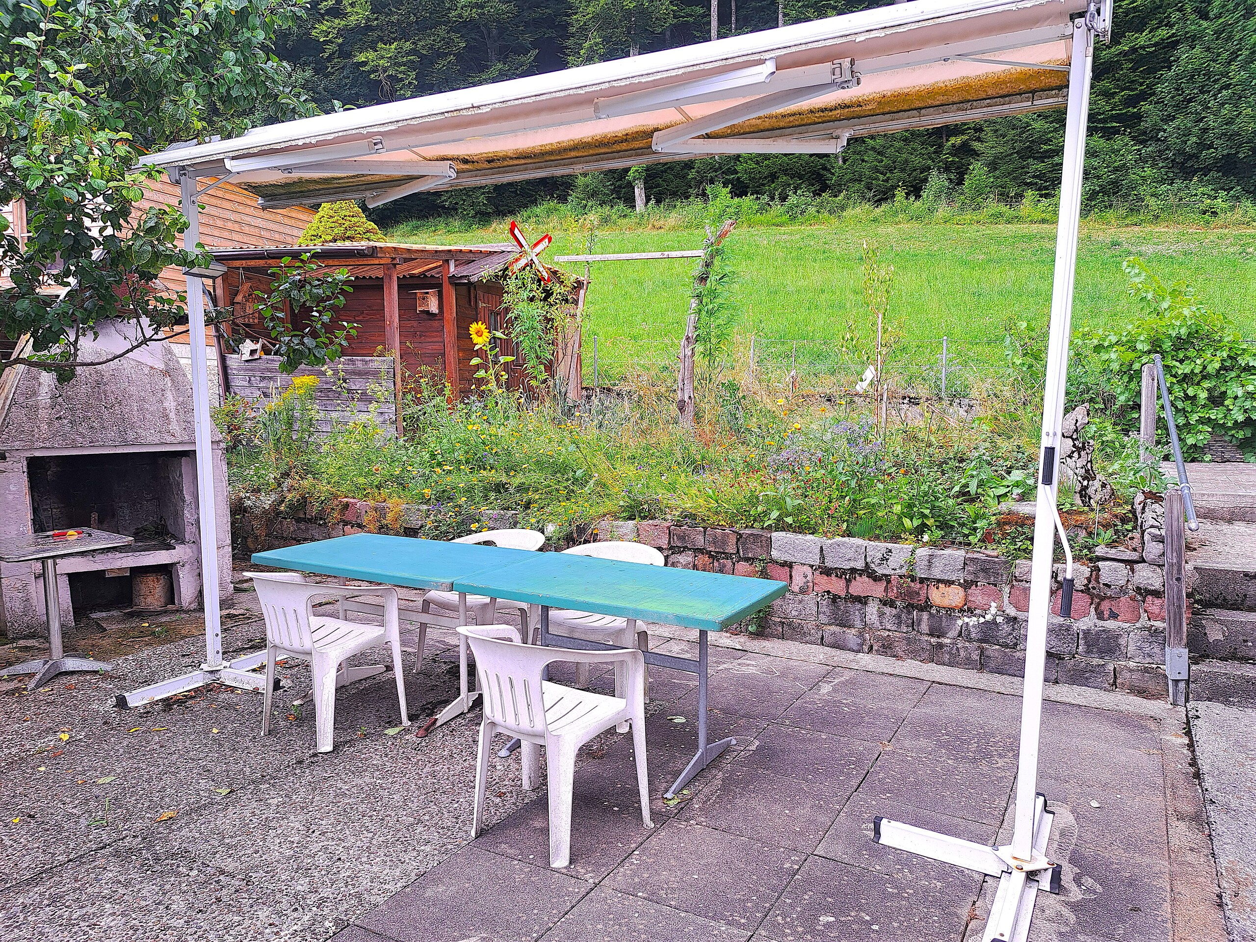 Überdachte Terrasse mit Grill und Gartenblick