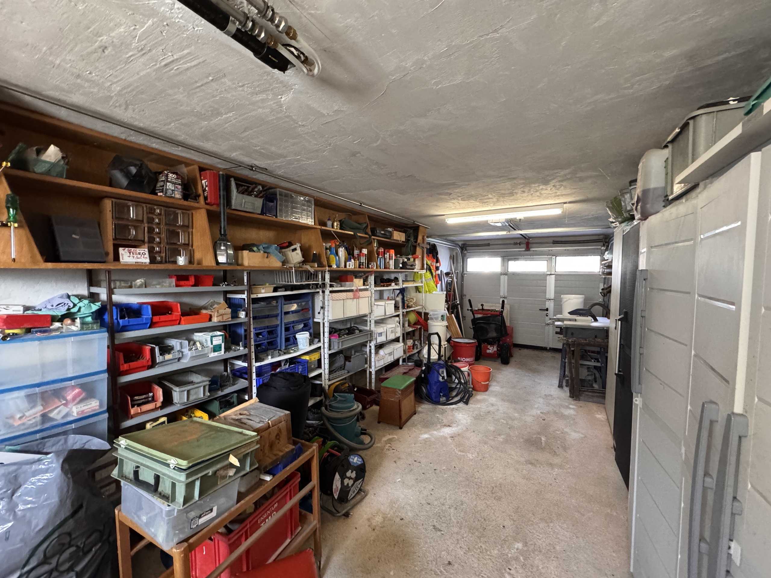 Aufgeräumte, aber vollgestellte Garage mit Werkstattlager