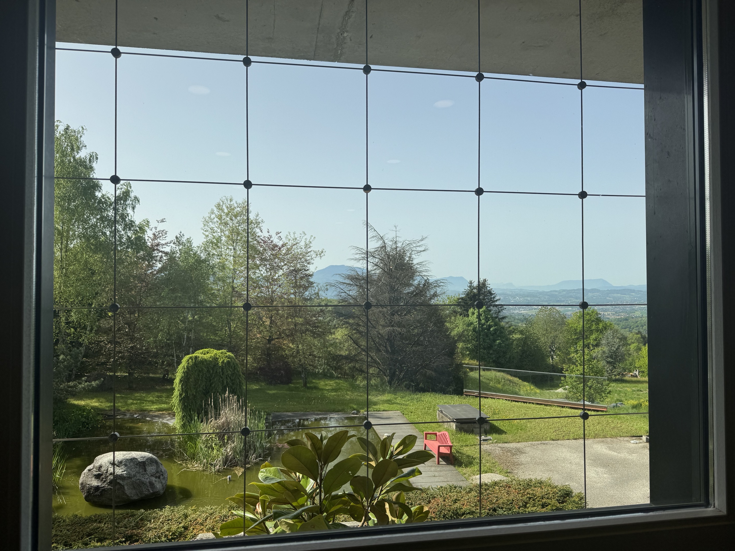 Gartenblick durch ein großes Fenster mit Gittersicherung