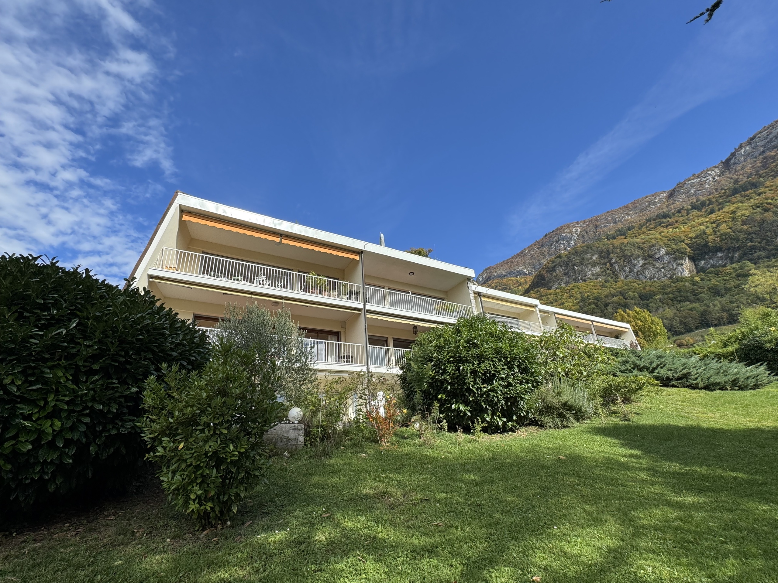 Außenansicht eines Wohngebäudes mit Balkon und Bergkulisse