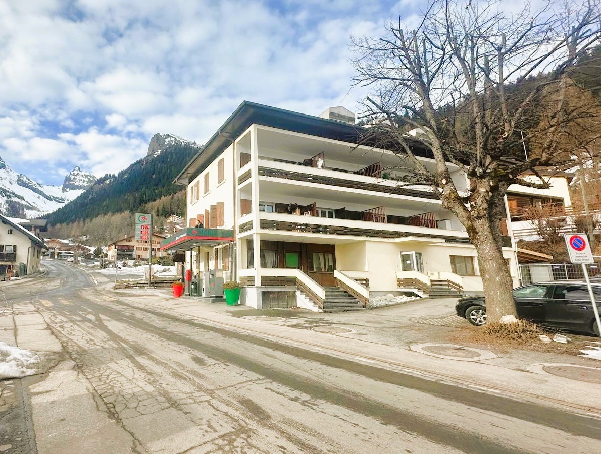 Alpines Mehrfamilienhaus an einer verschneiten Straße