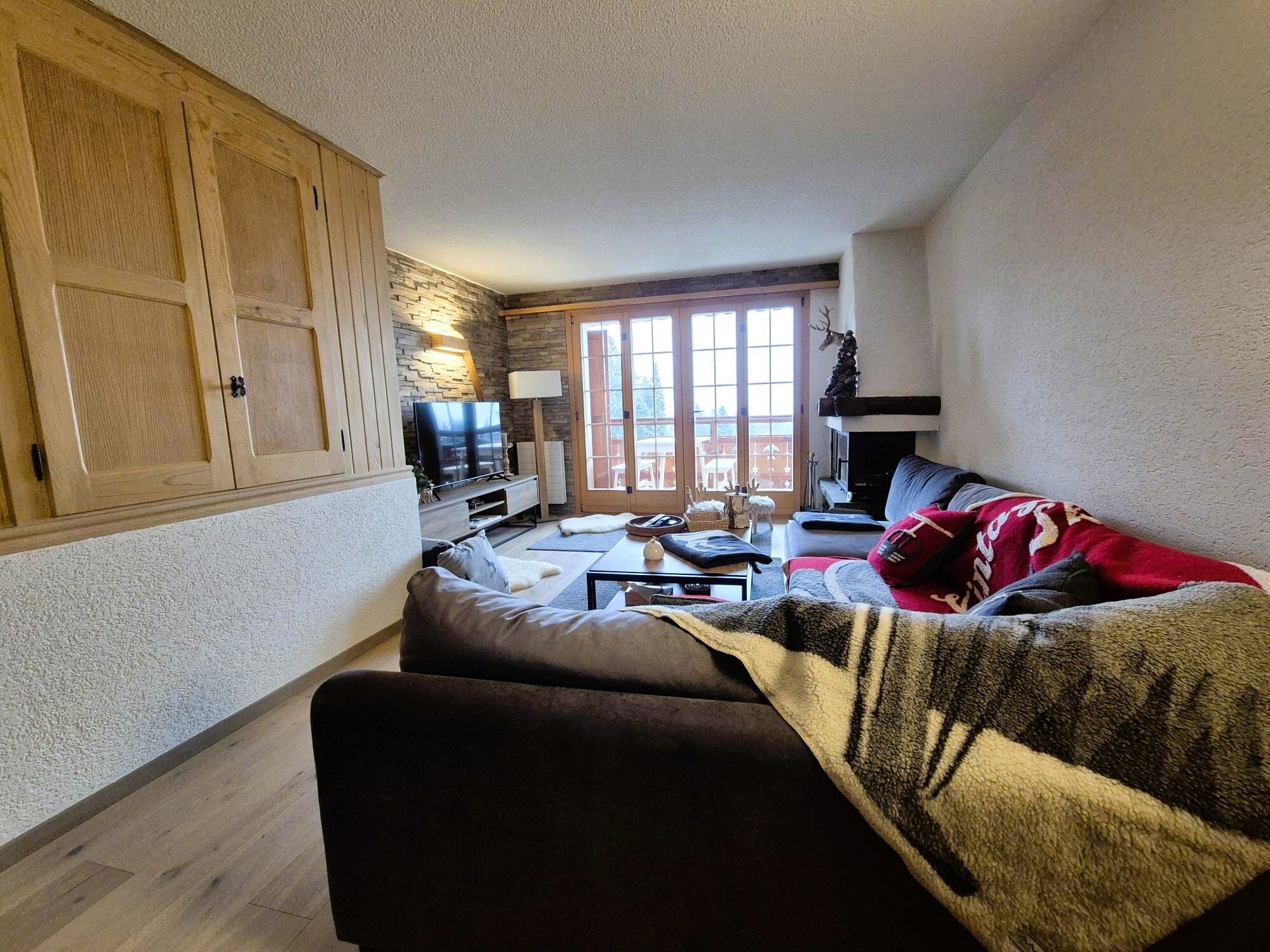 Gemütliches Wohnzimmer mit Kamin und Balkonblick