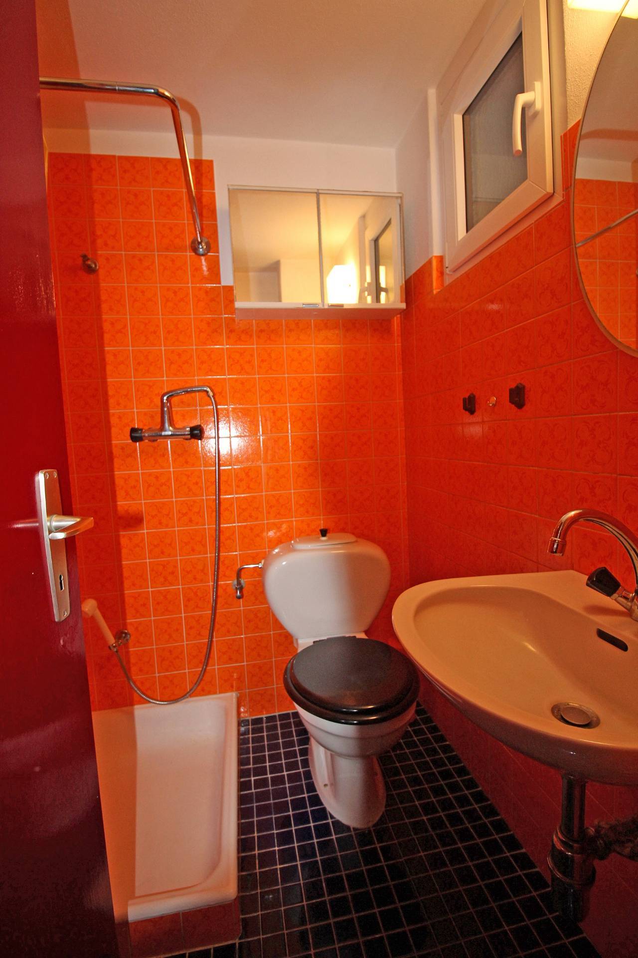 Kleines orangefarbenes Bad mit WC und Dusche