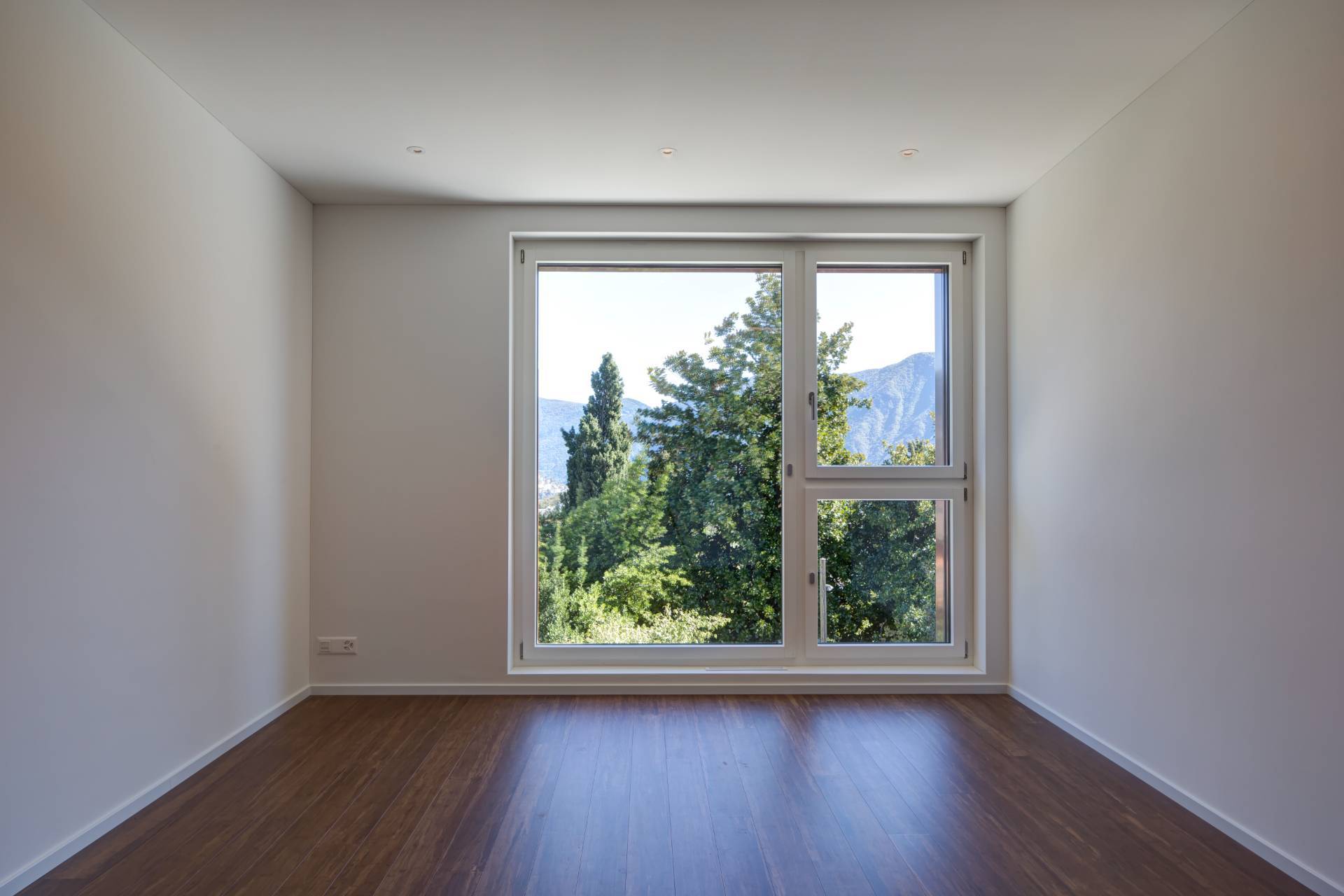 Leerer, helles Zimmer mit großem Fenster und Bergblick