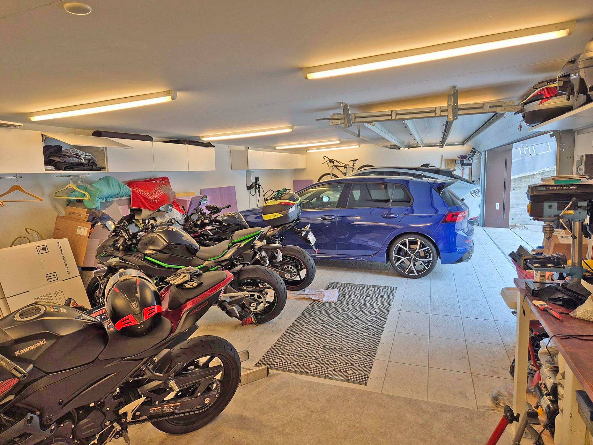 Gefüllte Doppelgarage mit Fahrzeugen und Arbeitsbereich