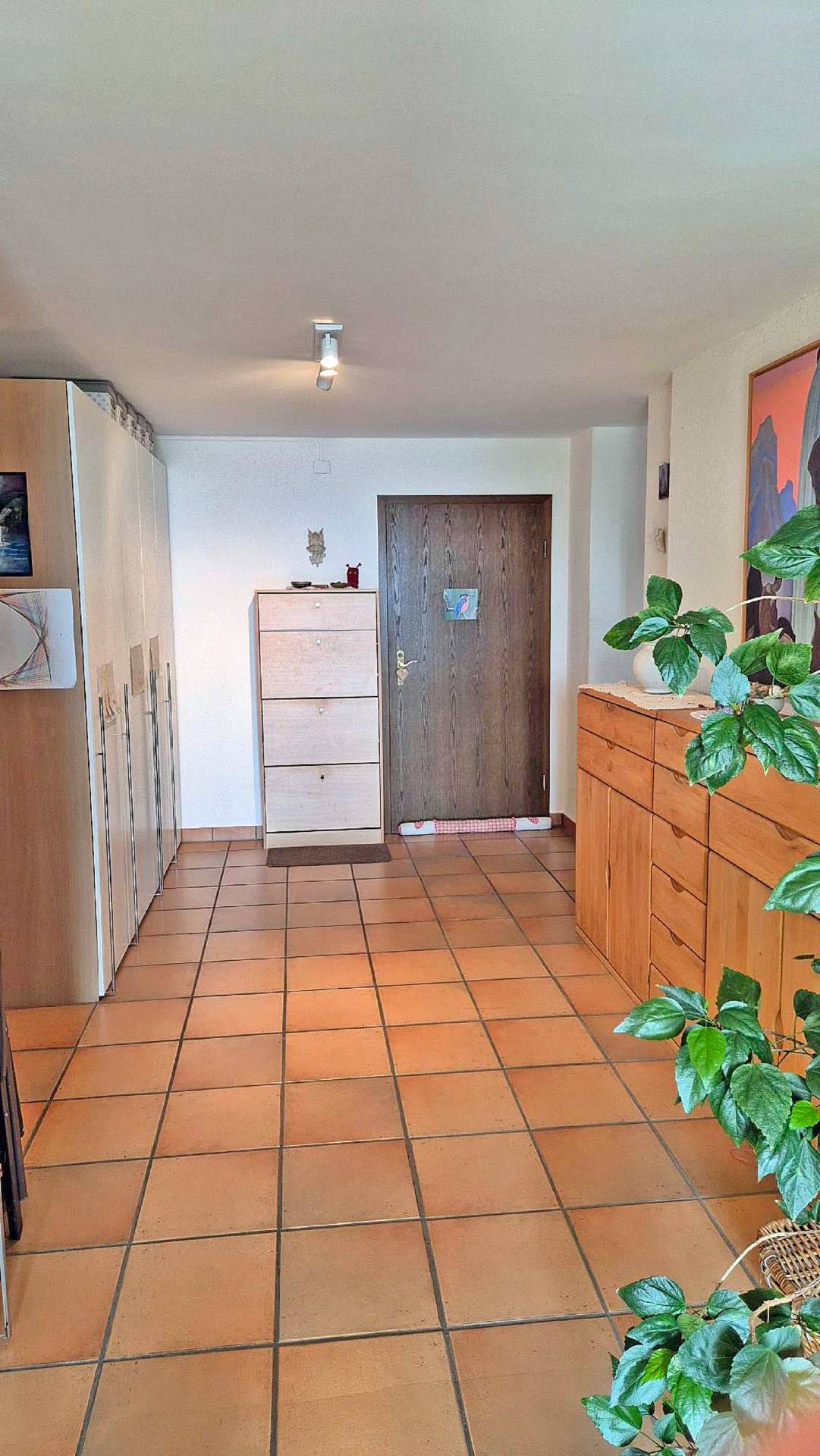 Heller Eingangsbereich mit Terrakottafliesen und Holzmöbeln