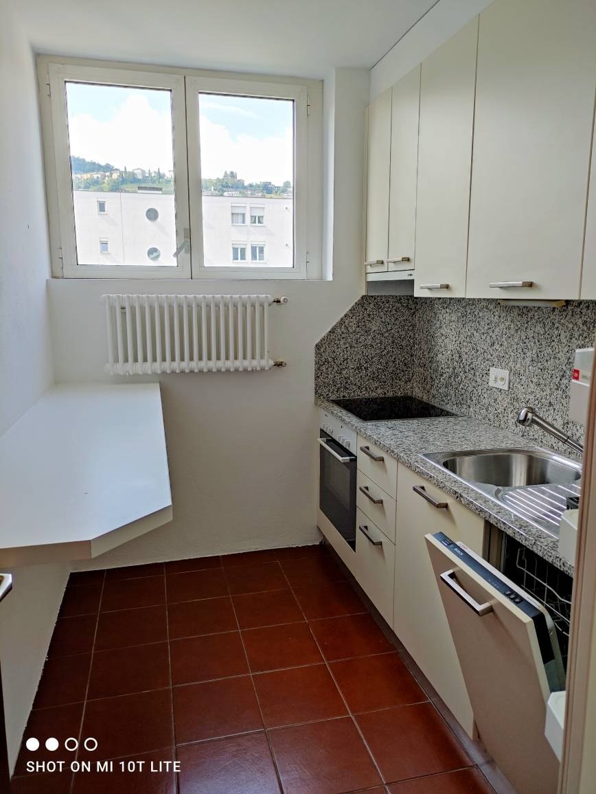 Kompakte Küche mit Fenster und Fliesenboden