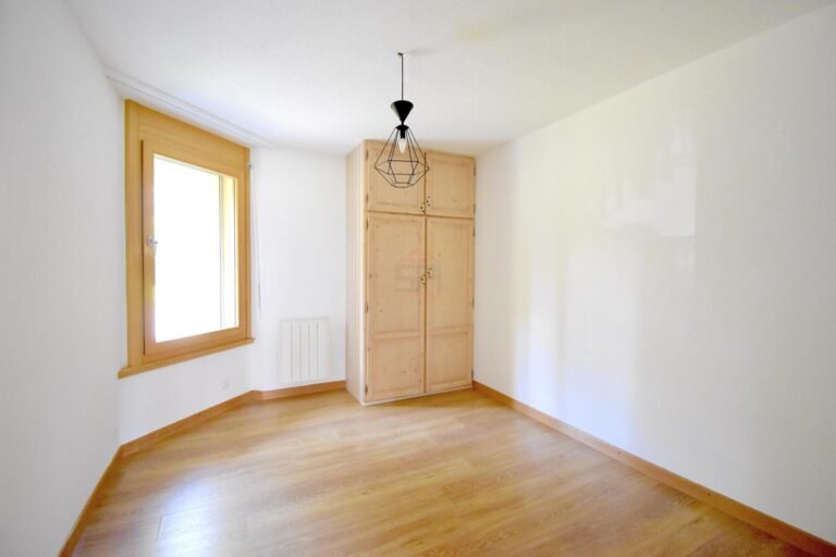 Helles, leeres Zimmer mit Holzfenster und Einbauschrank