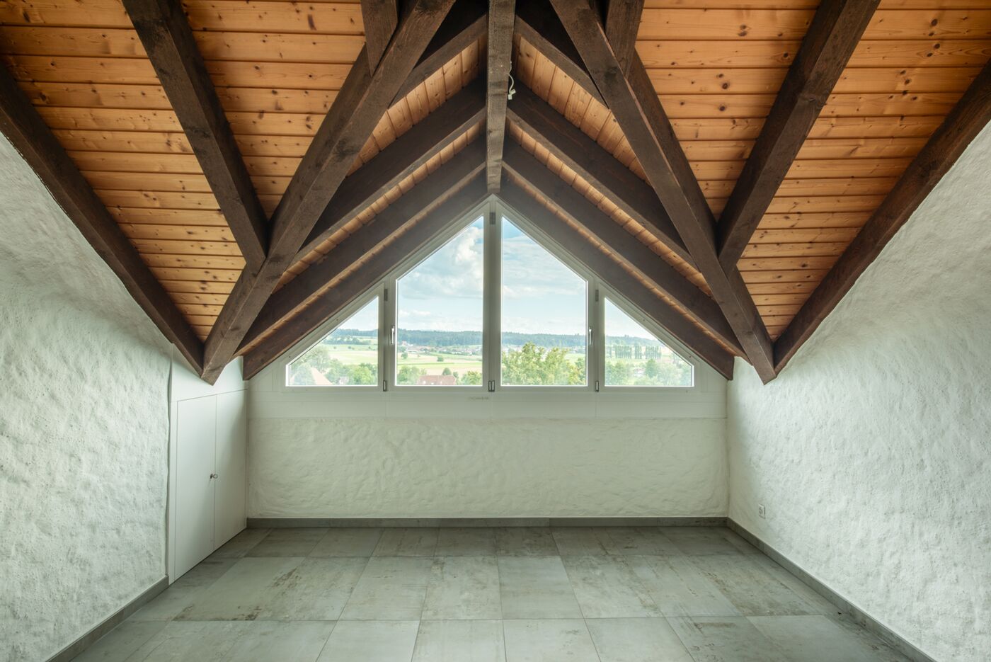 Dachgeschossraum mit Sichtdachstuhl und Panoramafenster