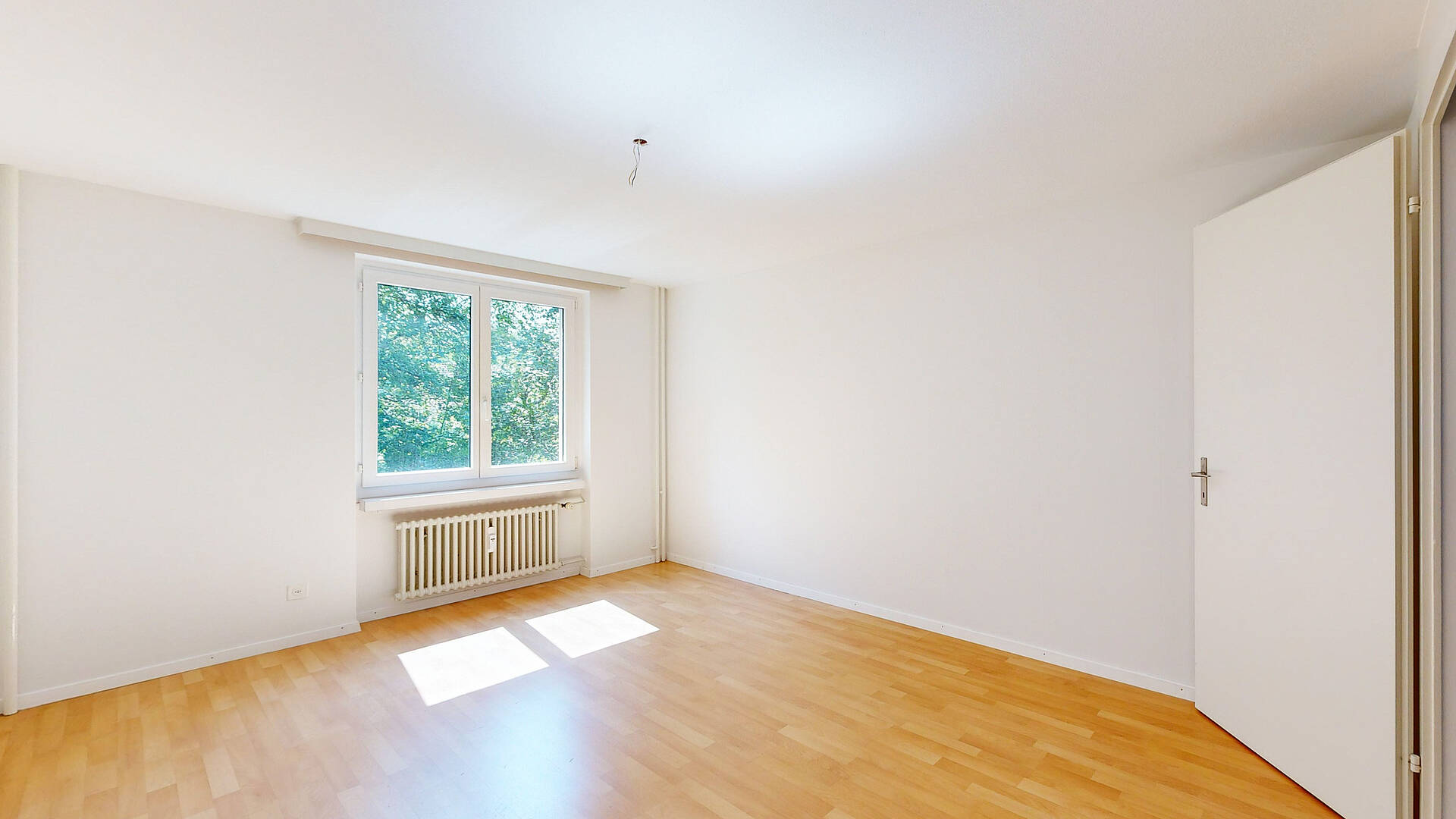 Helles, leeres Zimmer mit Fenster und Heizkörper