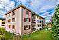 Mehrfamilienhaus mit hellem Putz und Balkon
