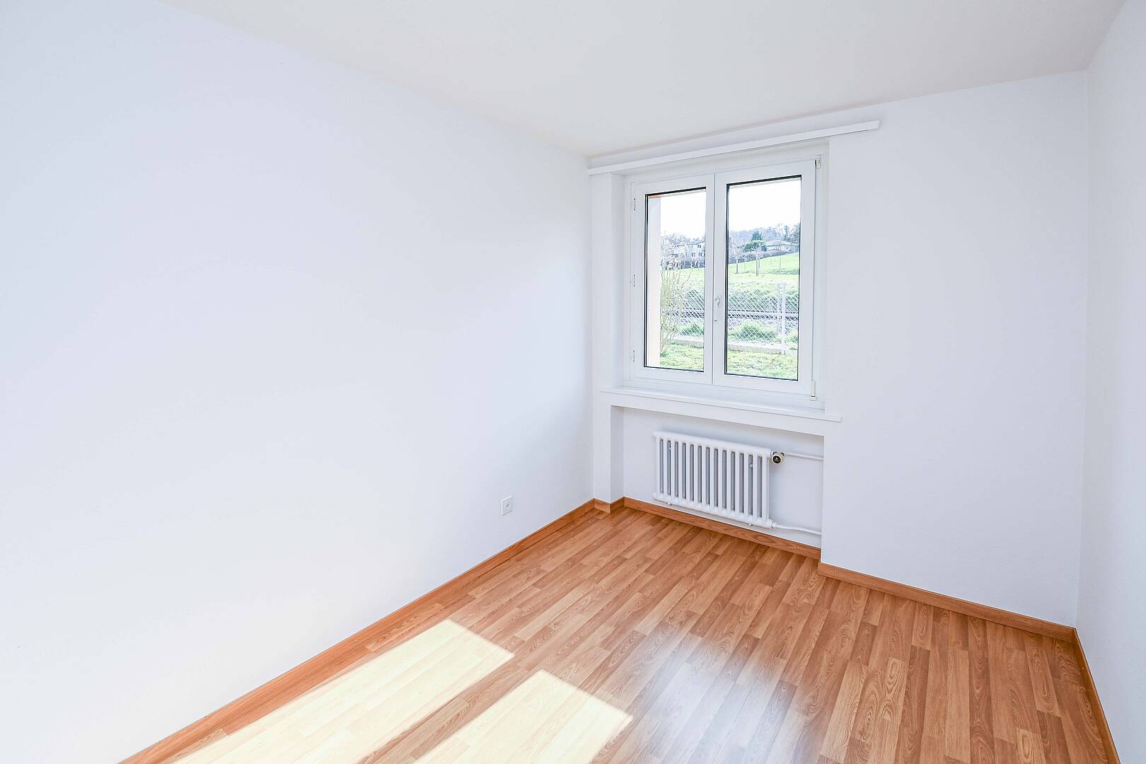 Helles leeres Zimmer mit Fenster und Heizkörper