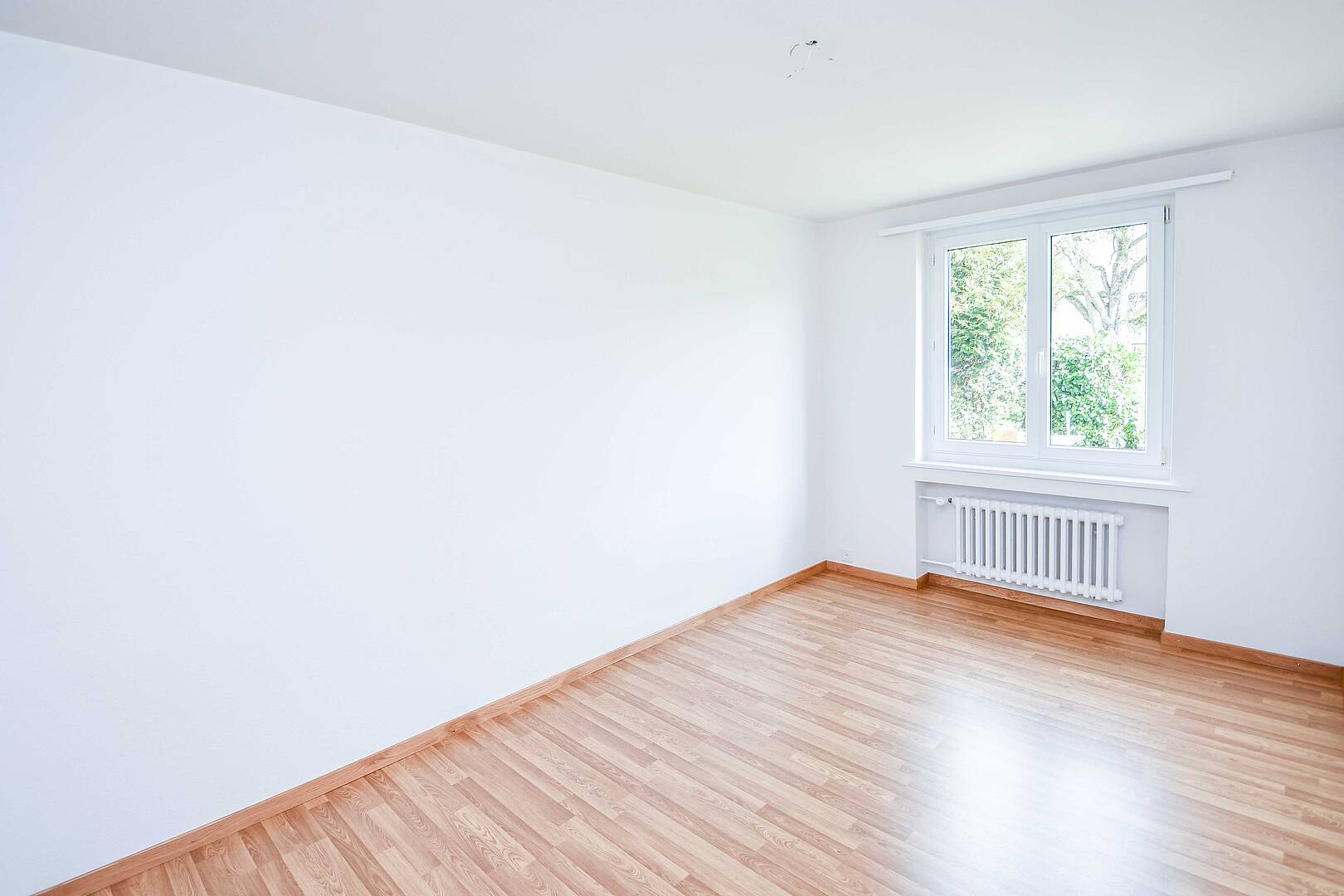 Leerer, heller Raum mit Fenster und Heizkörper