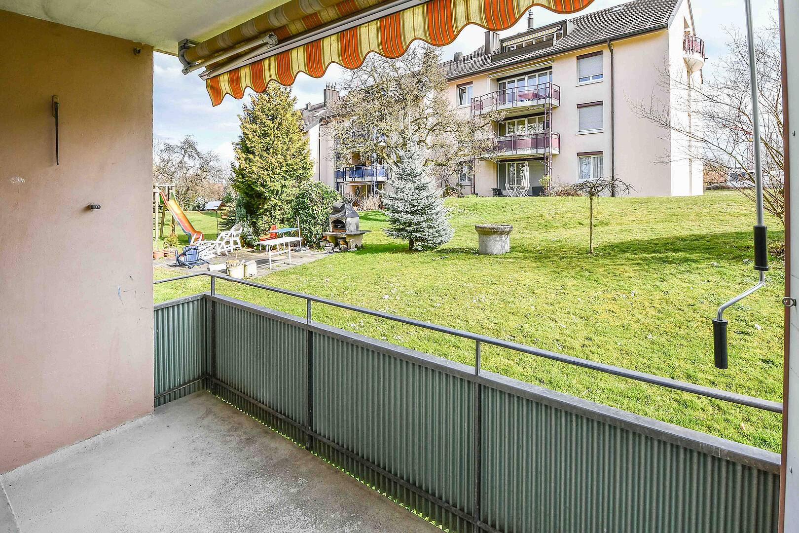 Balkon mit Blick auf Garten und Mehrfamilienhaus