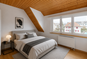 Modernes Schlafzimmer mit Holzdecke und großen Fenstern