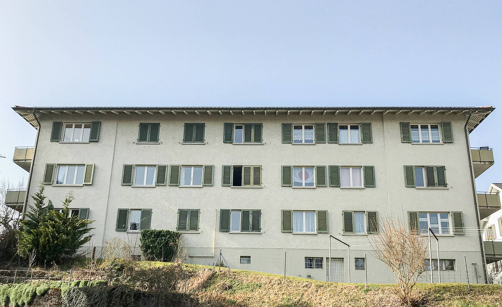 Mehrfamilienhaus mit grünen Fensterläden