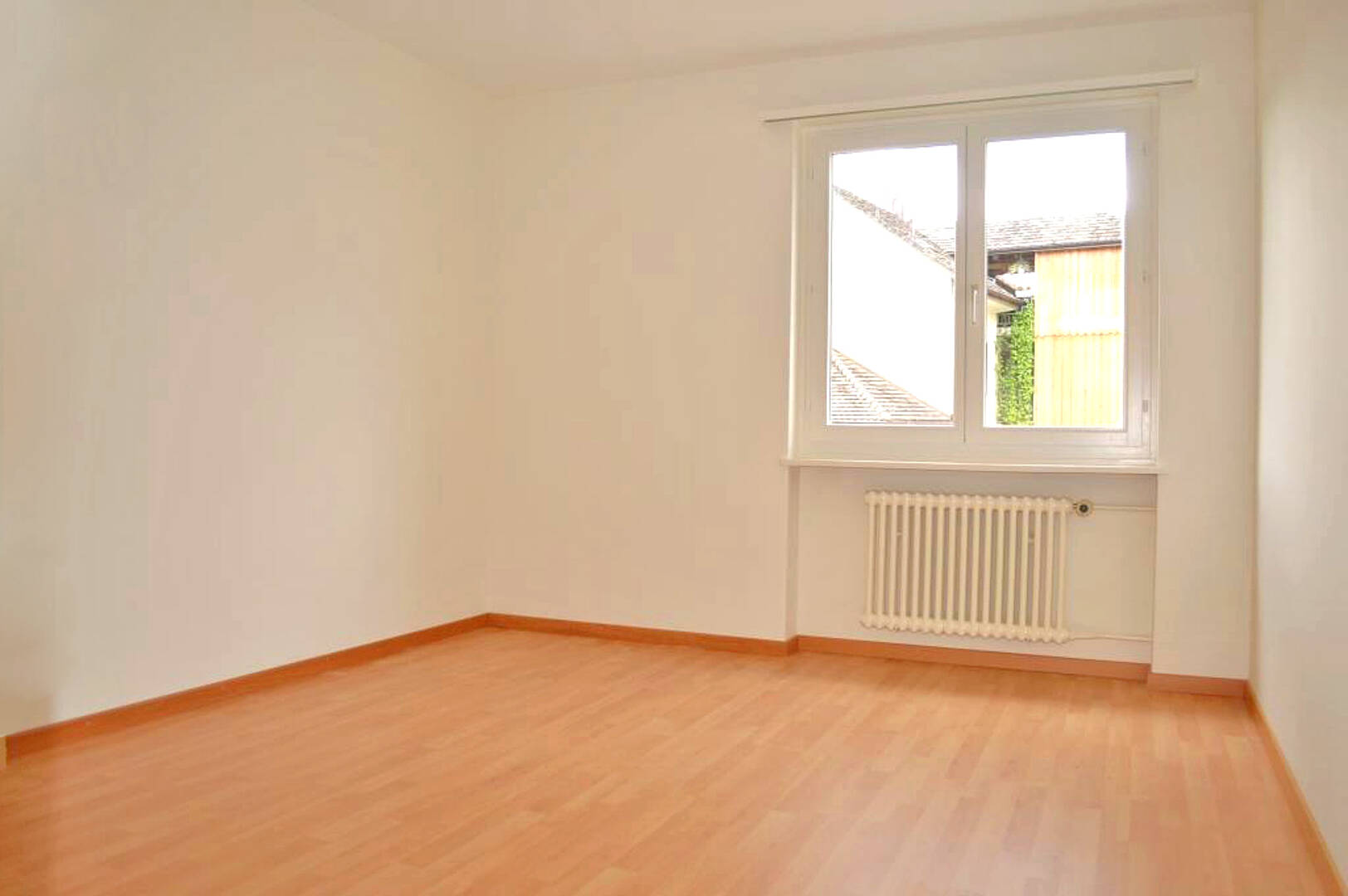 Leerer heller Raum mit Fenster und Heizkörper