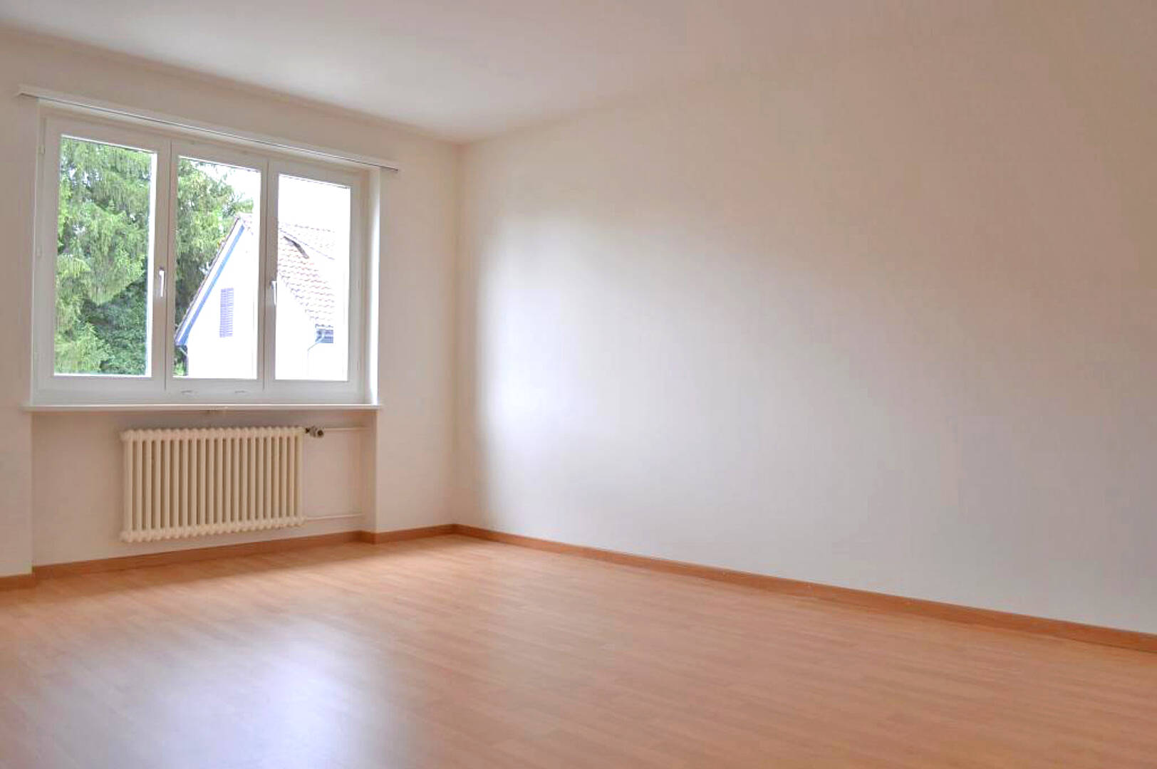 Leerer heller Raum mit Fenster und Heizkörper