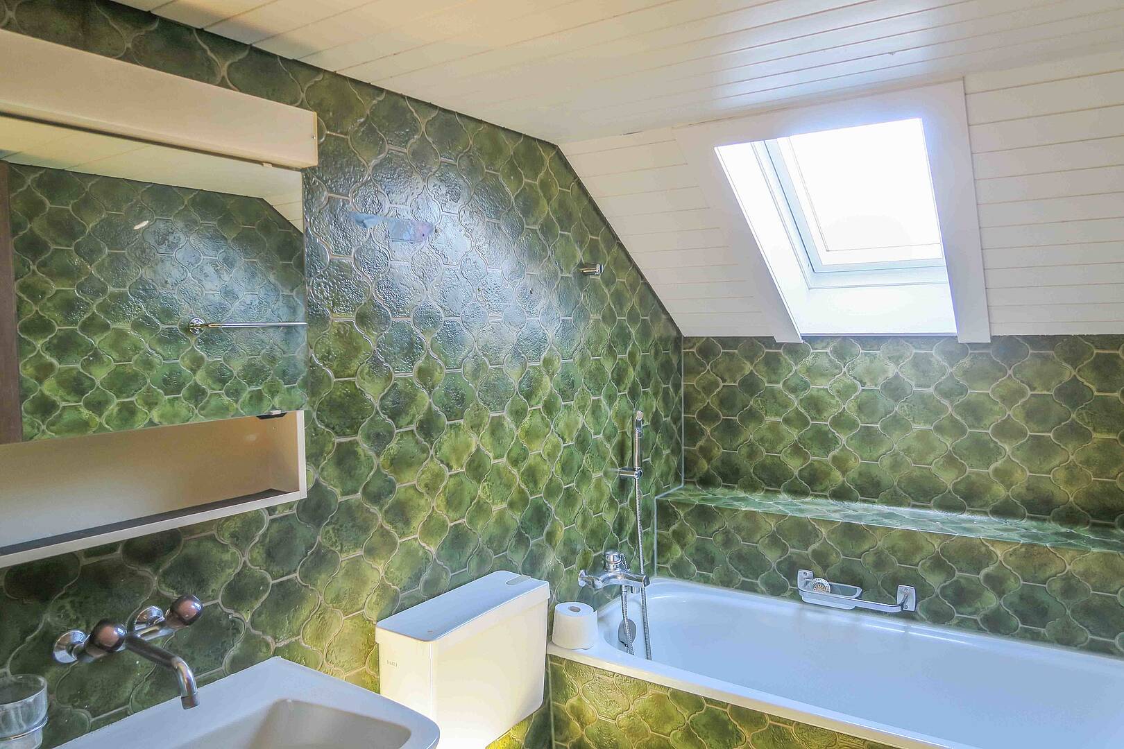 Badezimmer mit grünem Fliesenmuster und Dachfenster