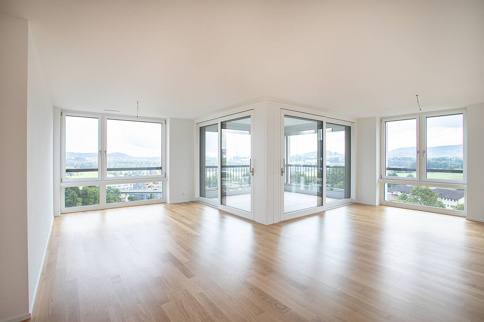 Heller, leerer Wohnraum mit Panoramafenstern und Balkonzugang