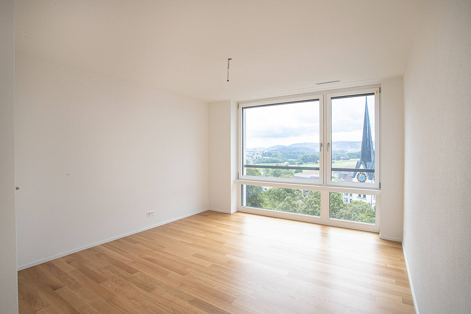 Heller leerer Raum mit großem Panoramafenster und Holzboden