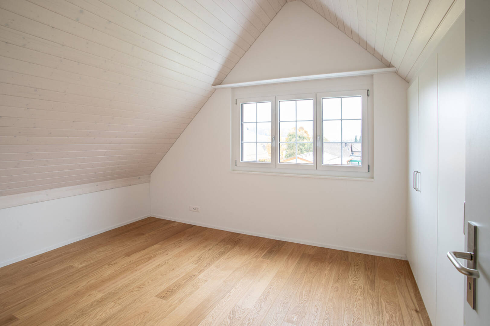 Helles Dachzimmer mit Fenster und Einbauschrank