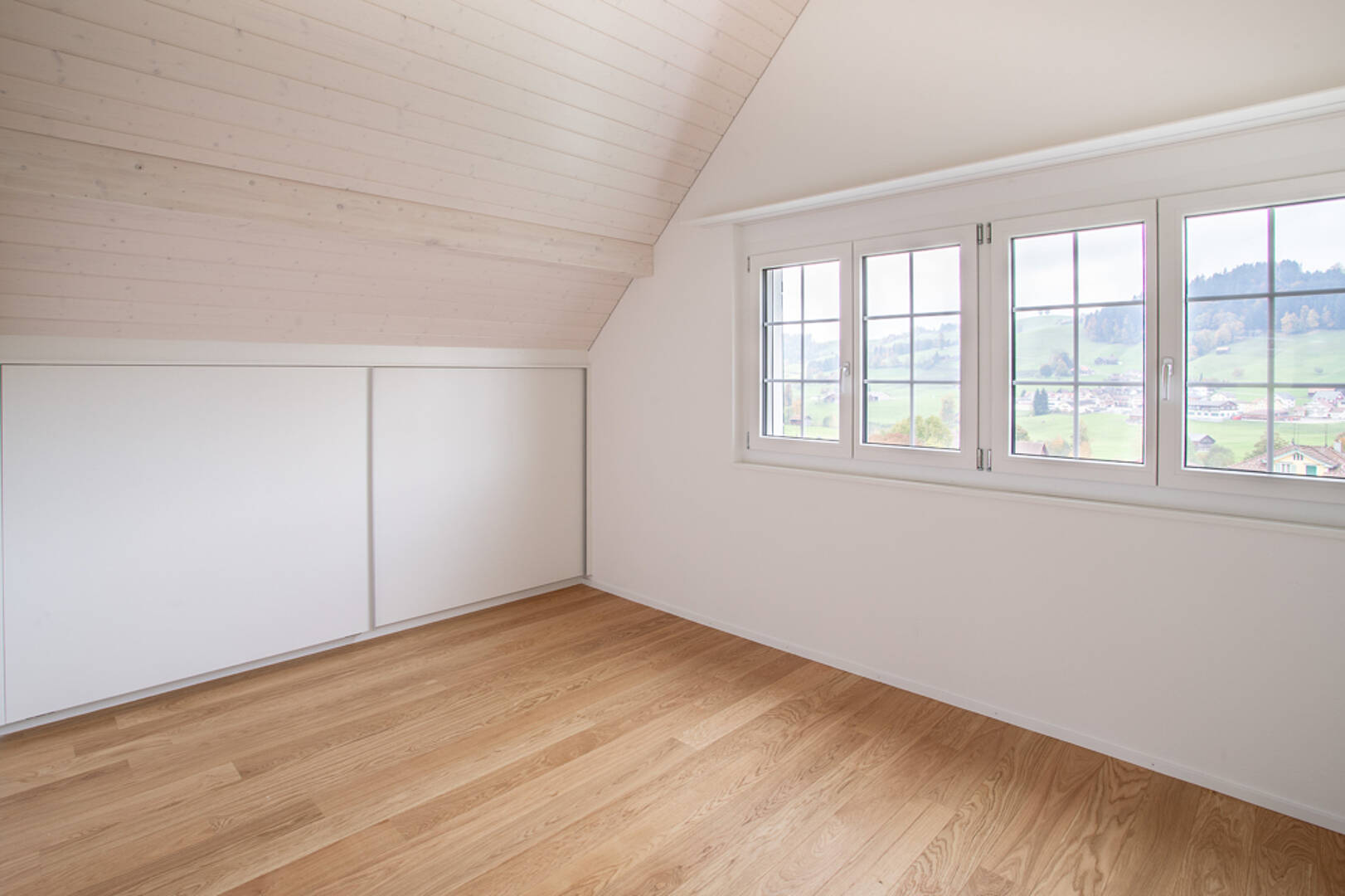Helles Dachgeschosszimmer mit Holzdecke und Ausblick
