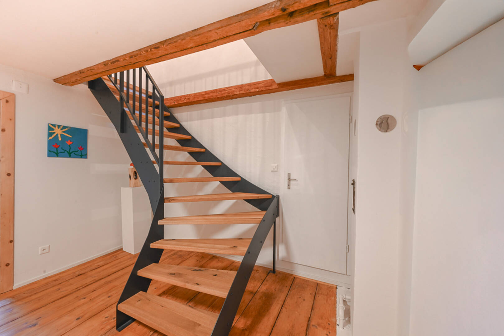 Treppenaufgang mit sichtbaren Holzbalken