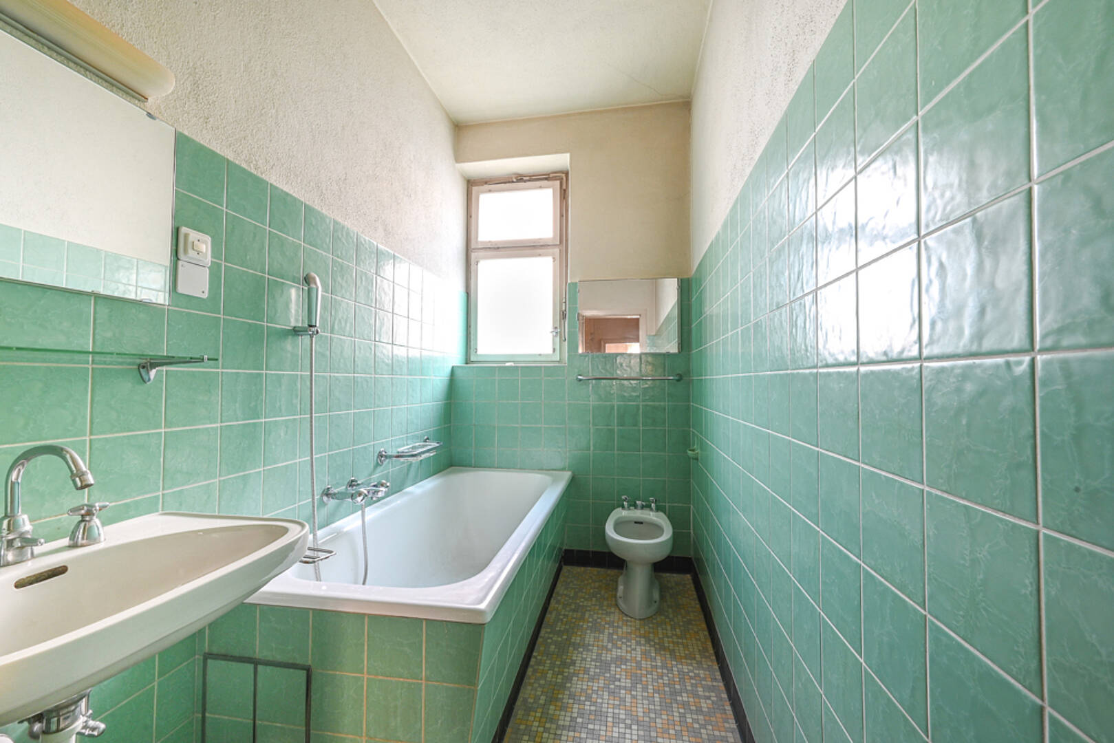 Kleines Bad mit mintgrünen Fliesen und Badewanne