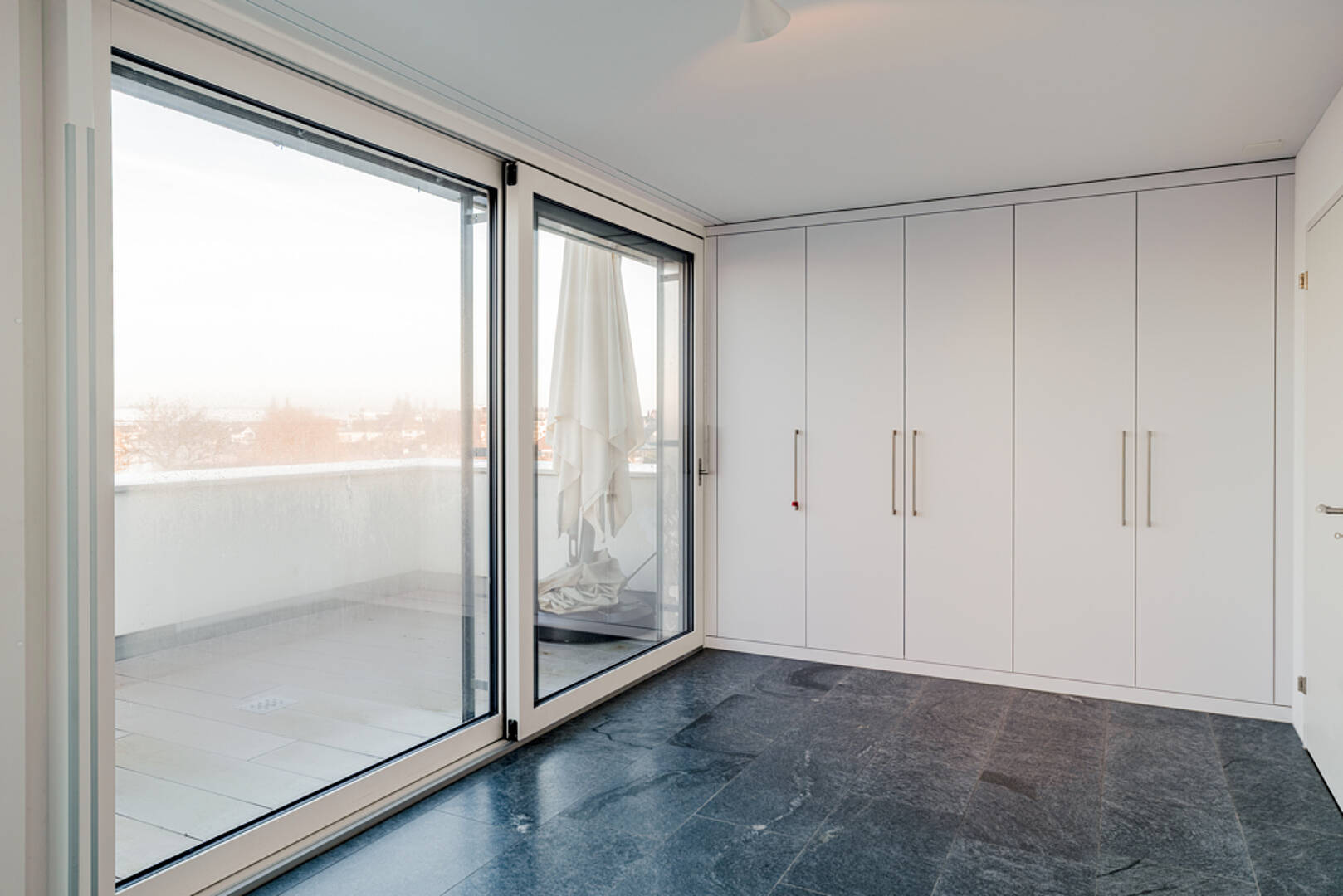 Heller Raum mit Einbauschrank und Balkonzugang