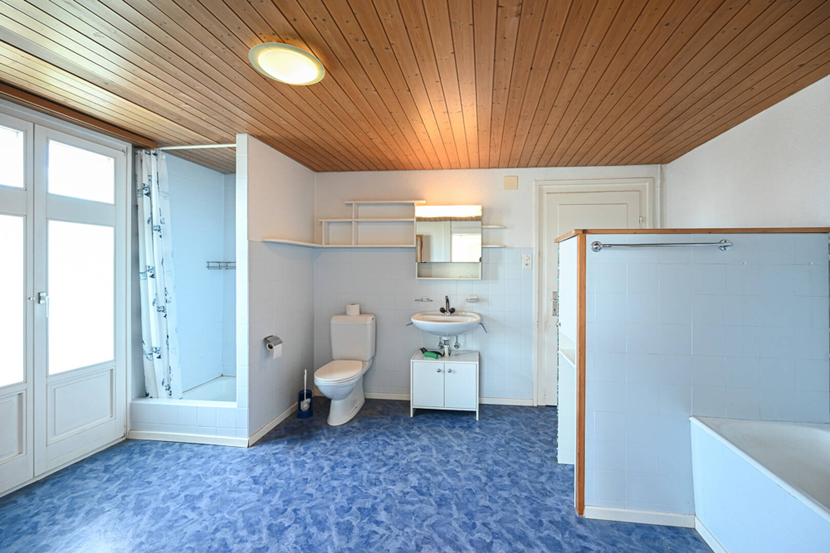 Badezimmer mit Holzdecke und blauem Boden