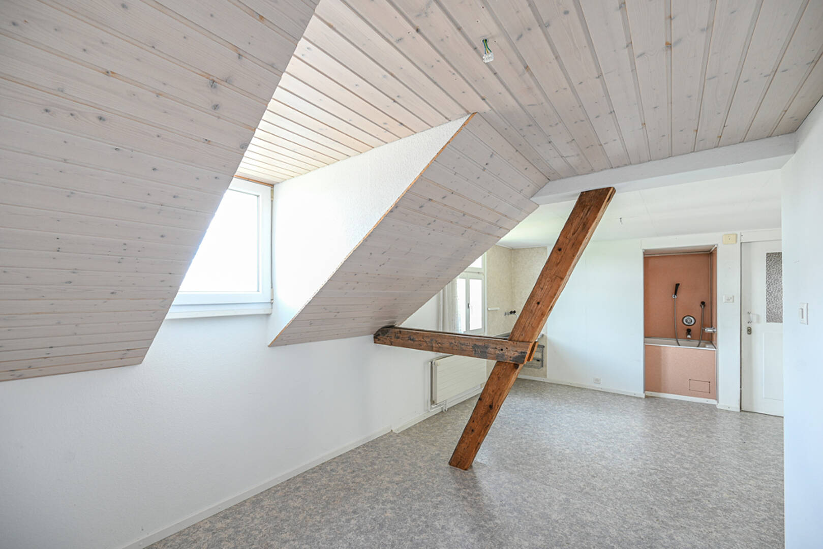 Dachgeschossraum mit sichtbarer Holzbalkenstruktur