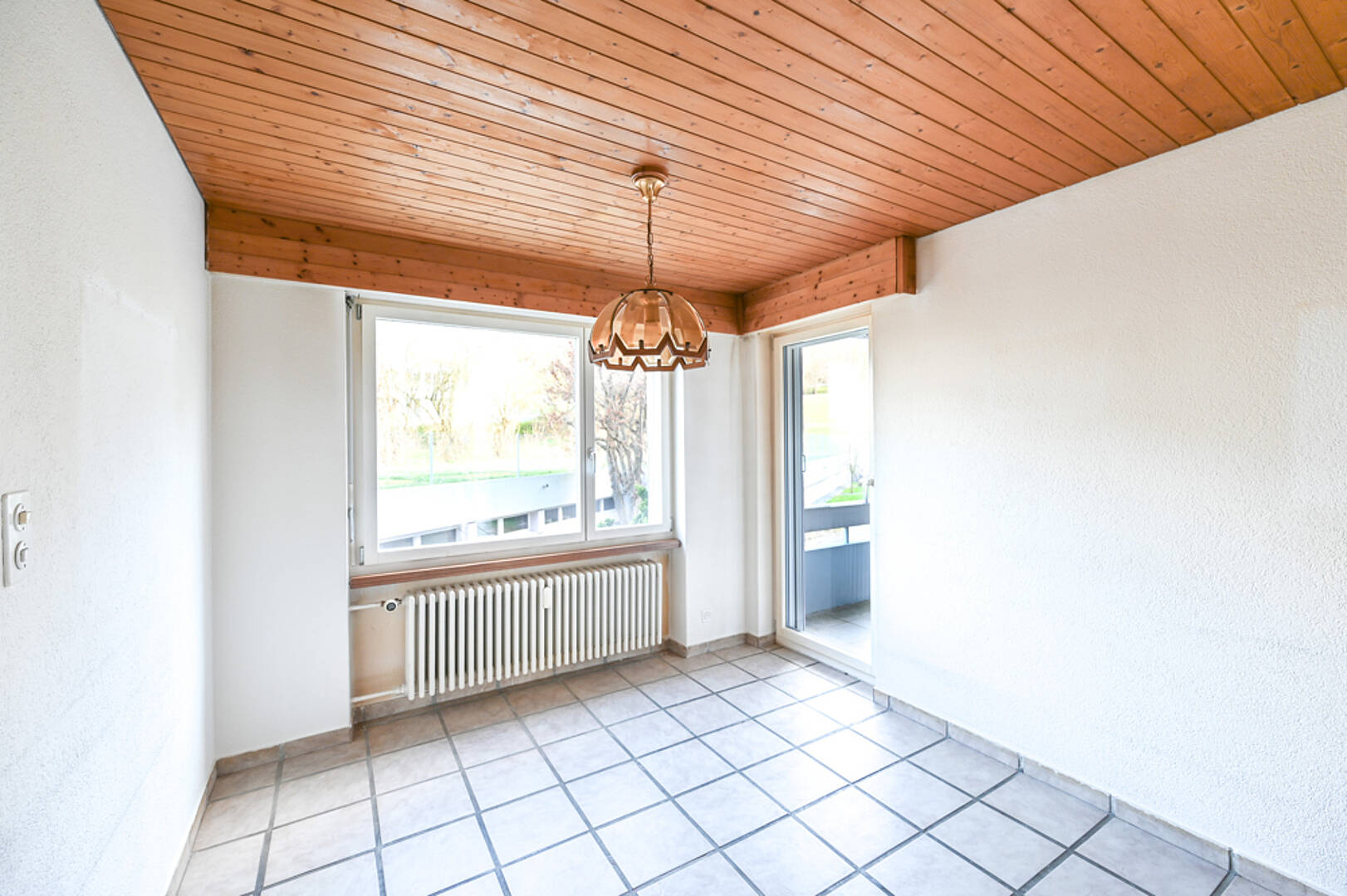 Heller Raum mit Holzdecke und Fliesenboden