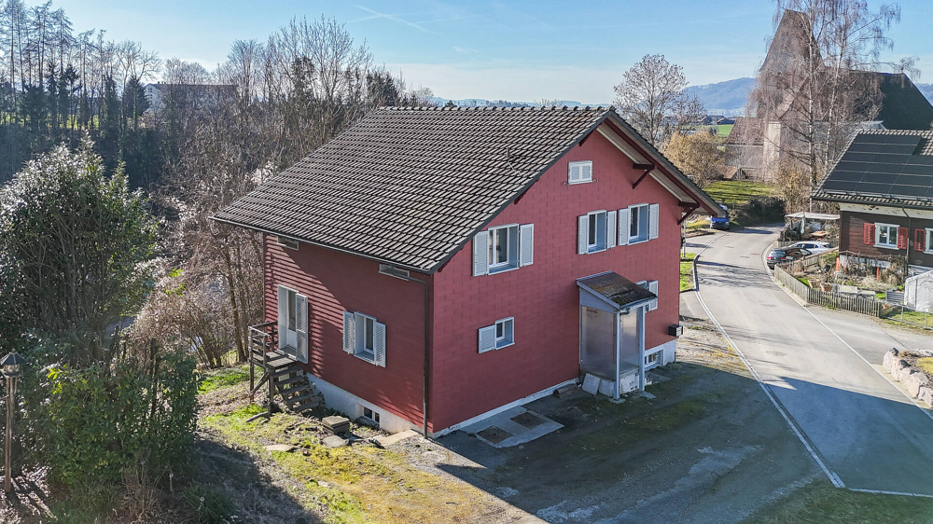 Rotes Einfamilienhaus mit Walmdach in ländlicher Umgebung