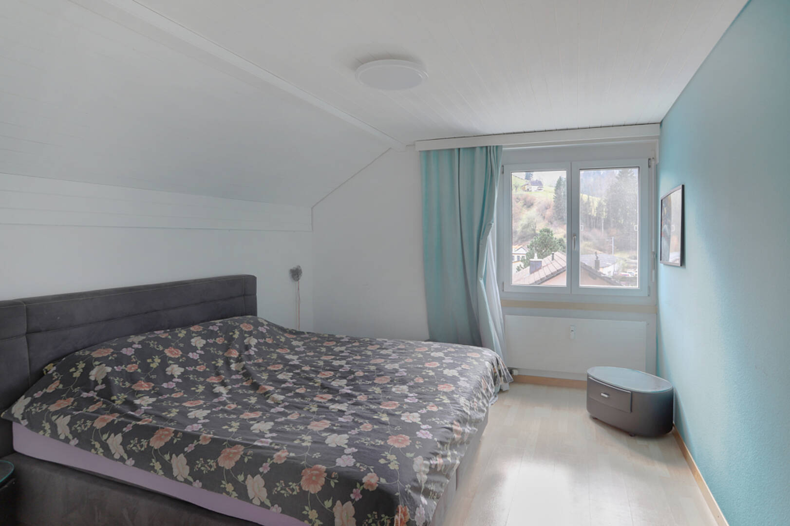 Schlafzimmer mit Dachschräge und Fensterblick