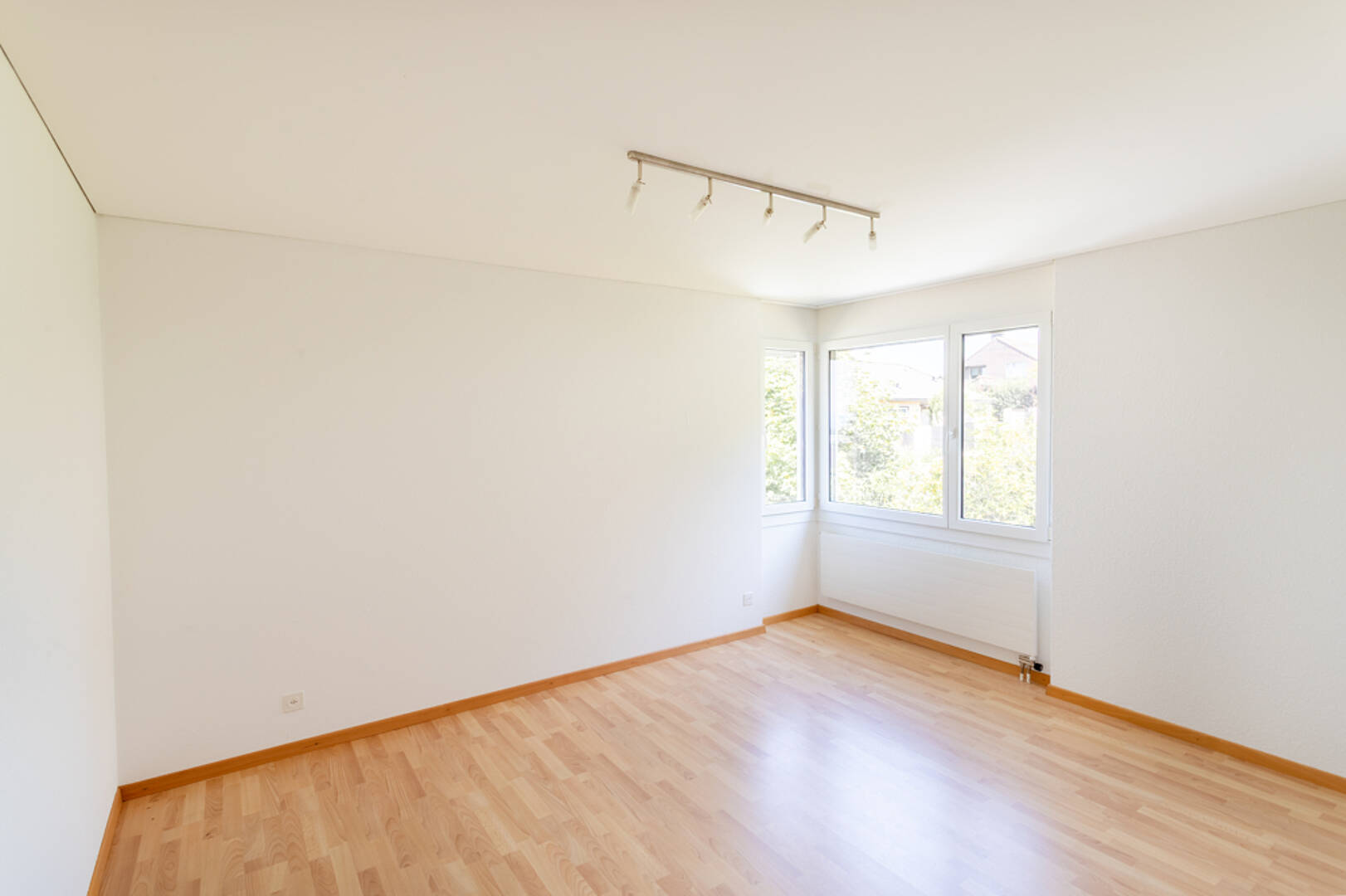 Heller leerer Raum mit Holzfußboden und Fensterfront