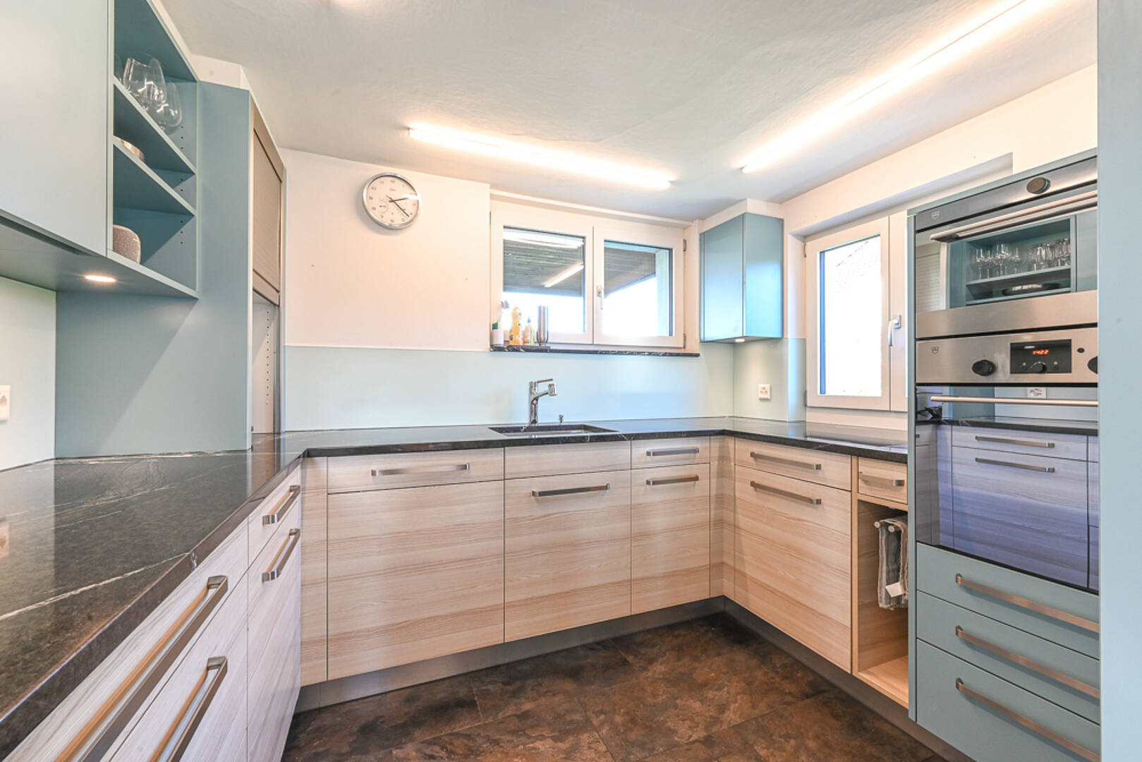 Moderne U-förmige Küche mit hellen Holzfronten und dunkler Arbeitsplatte
