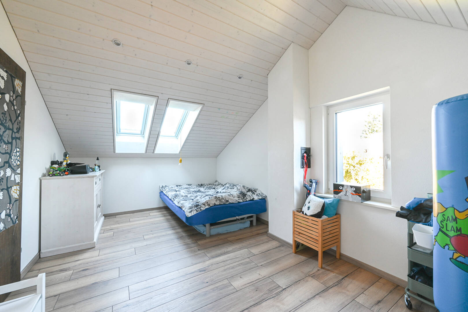 Helles Dachzimmer mit Bett und Dachfenstern
