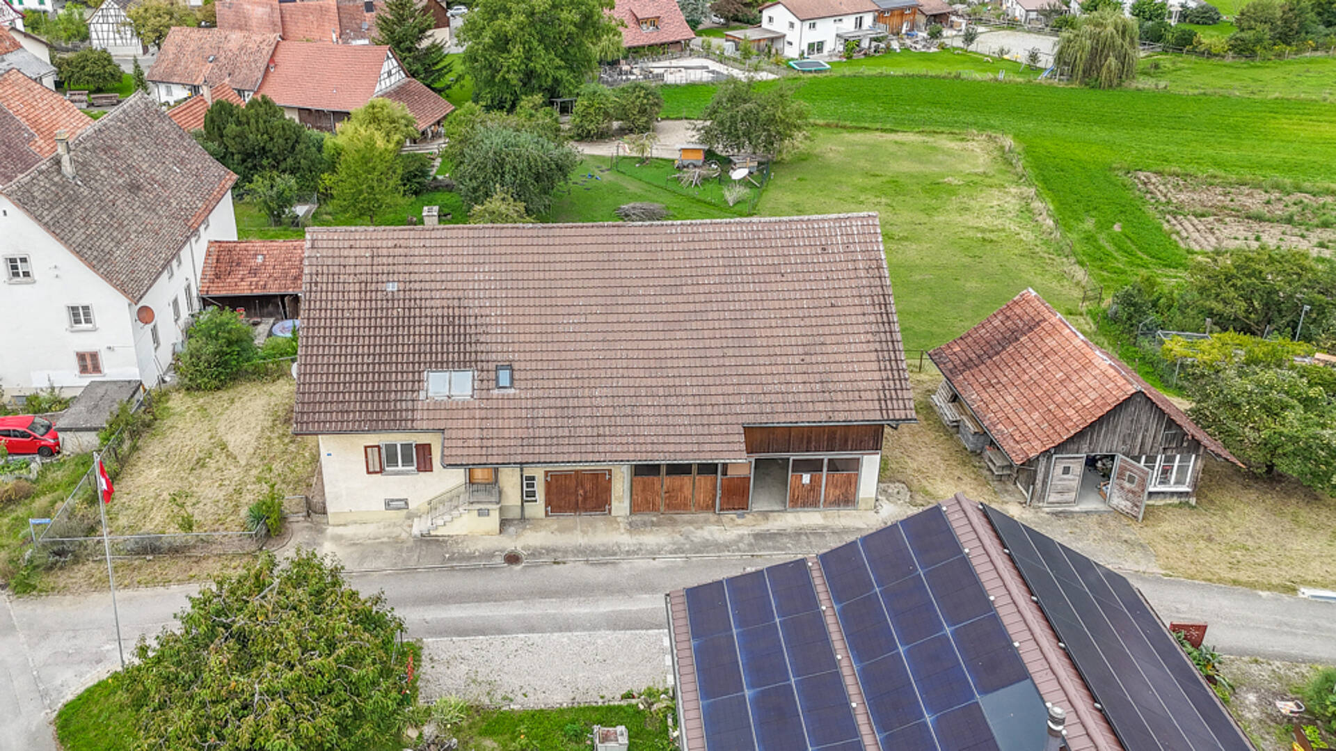 Luftaufnahme eines ländlichen Wohnhauses mit Nebengebäude und Solardach