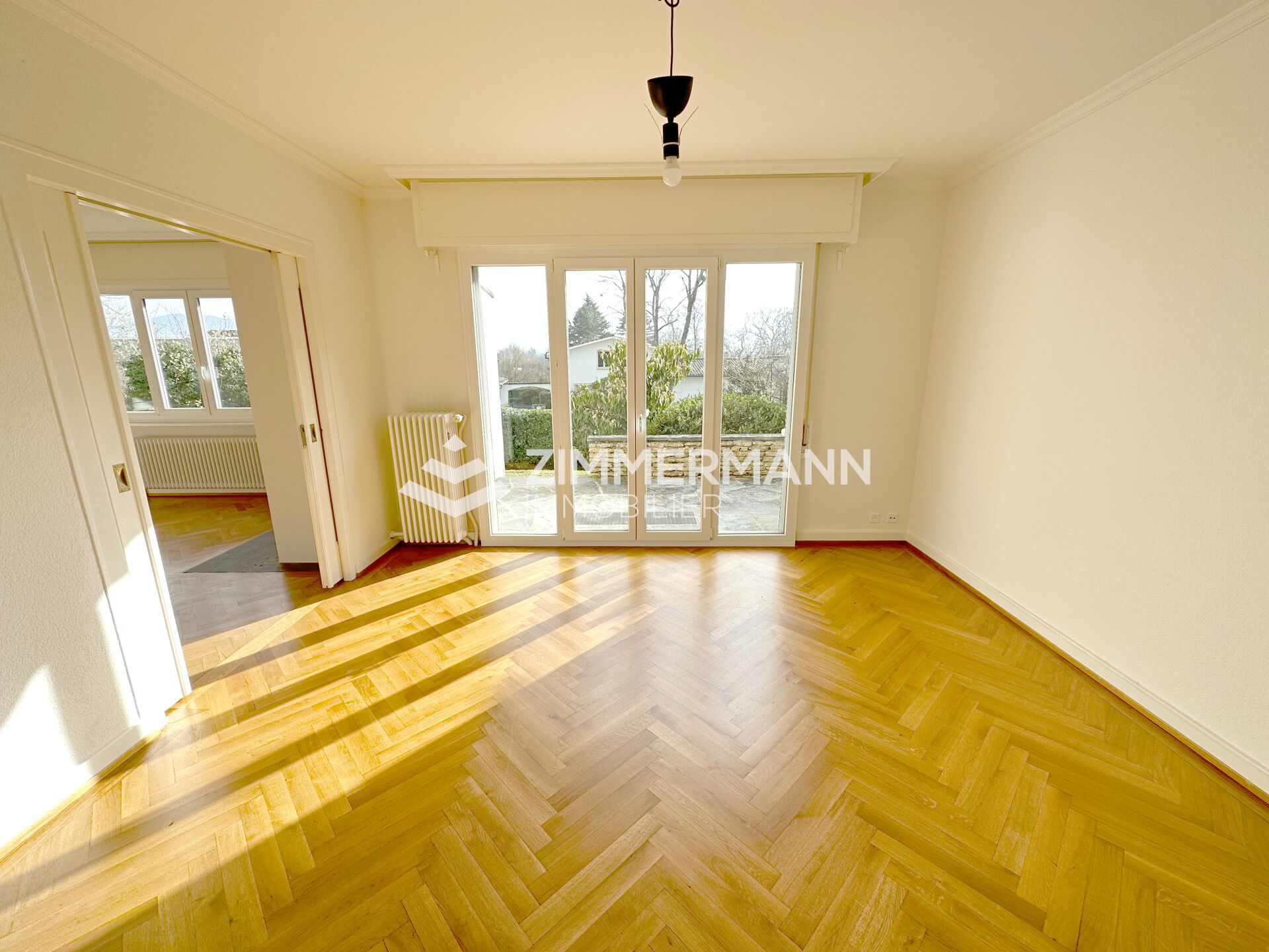 Helles leeres Zimmer mit Parkett und Balkon-/Terrassentür